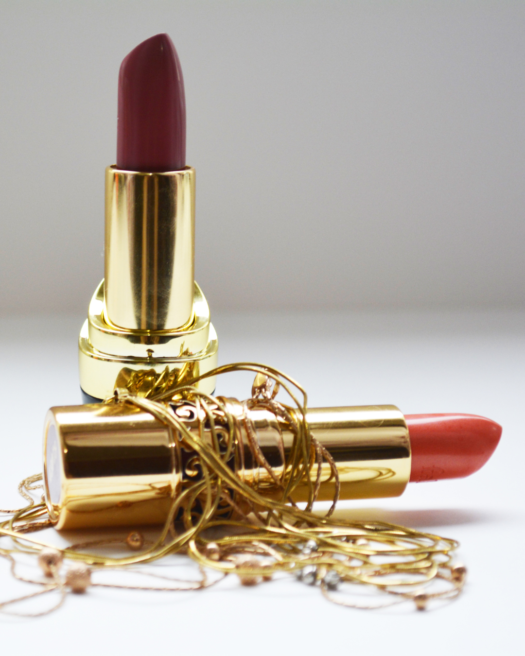 A gold lipstick is sitting on top of a gold chain