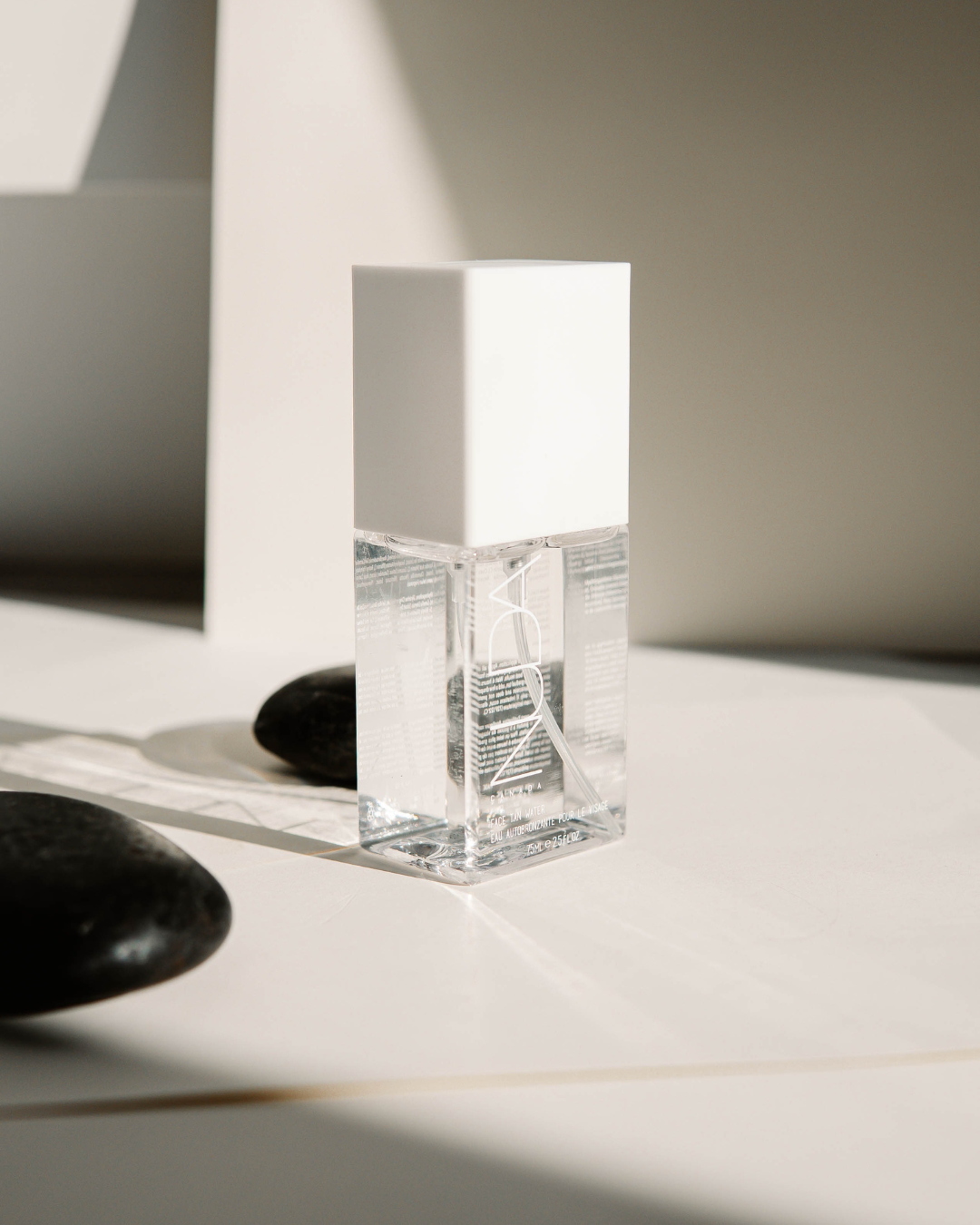 A bottle of perfume is sitting on a table next to some rocks.