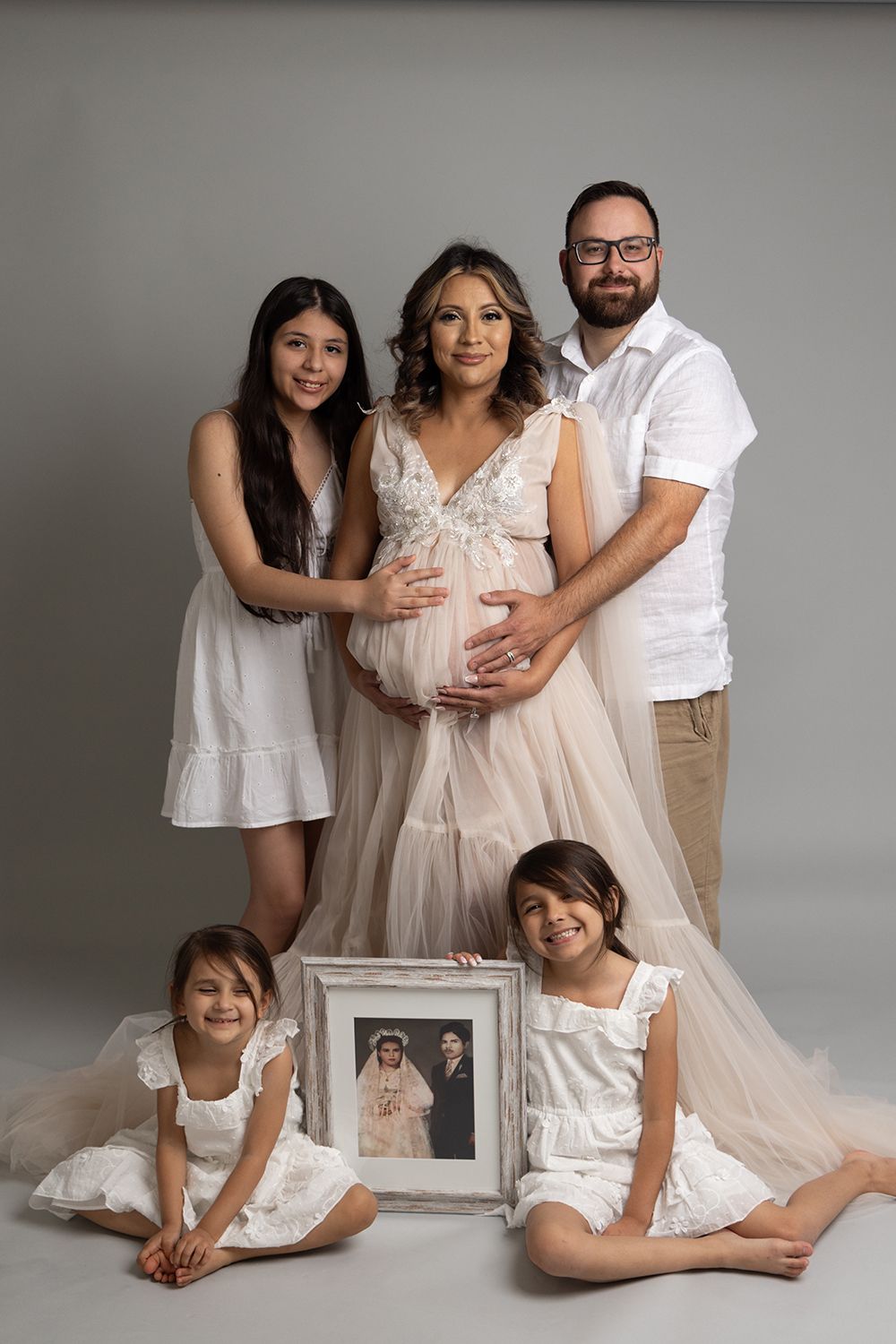 A pregnant woman is posing for a picture with her family