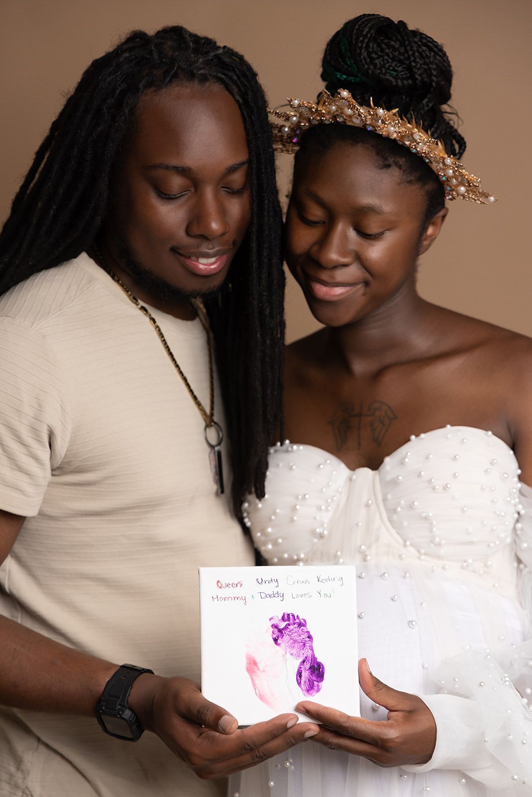 A man and a woman are holding a card with a baby footprint on it