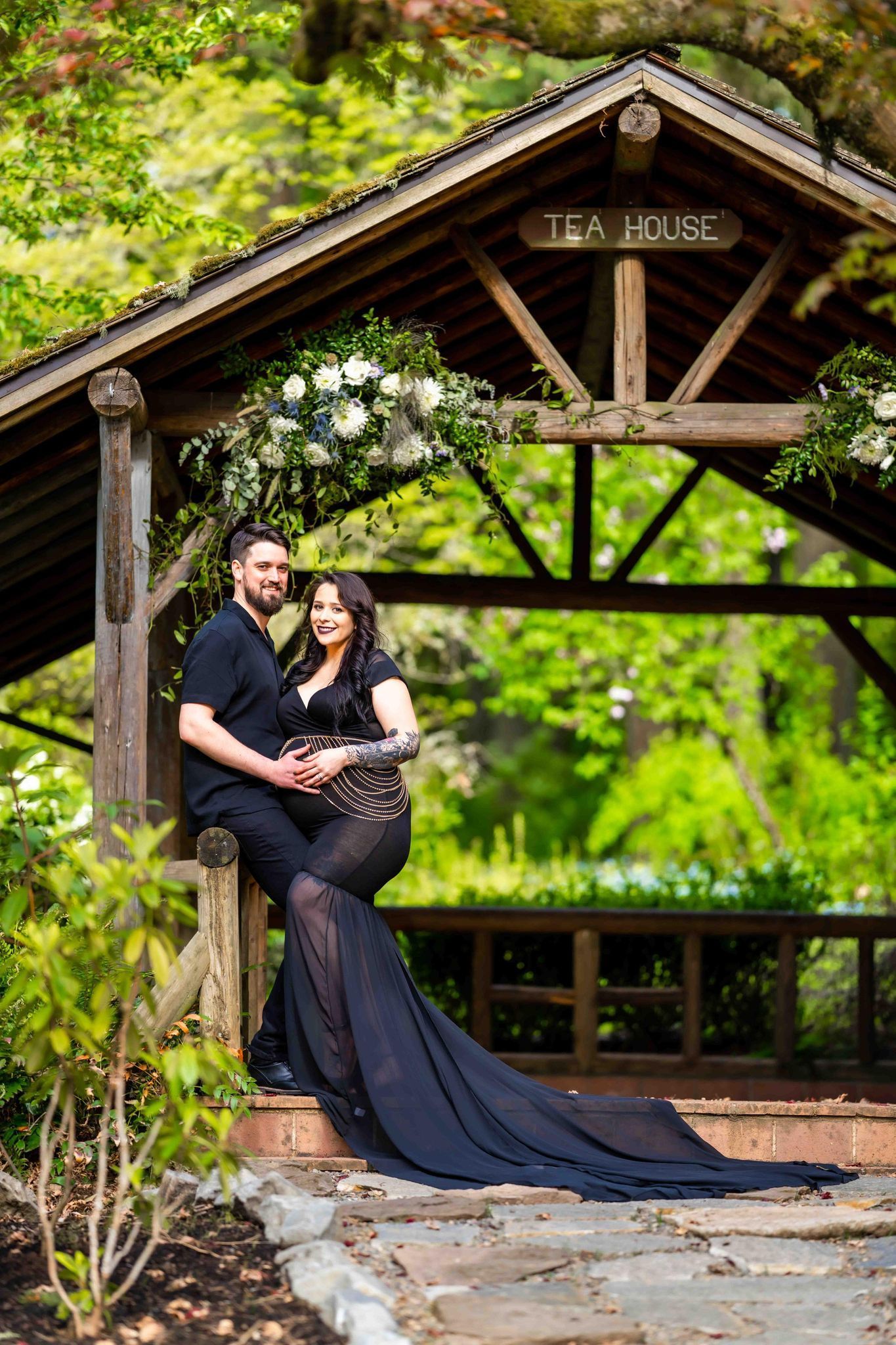 A man and a pregnant woman are sitting under a gazebo in a park