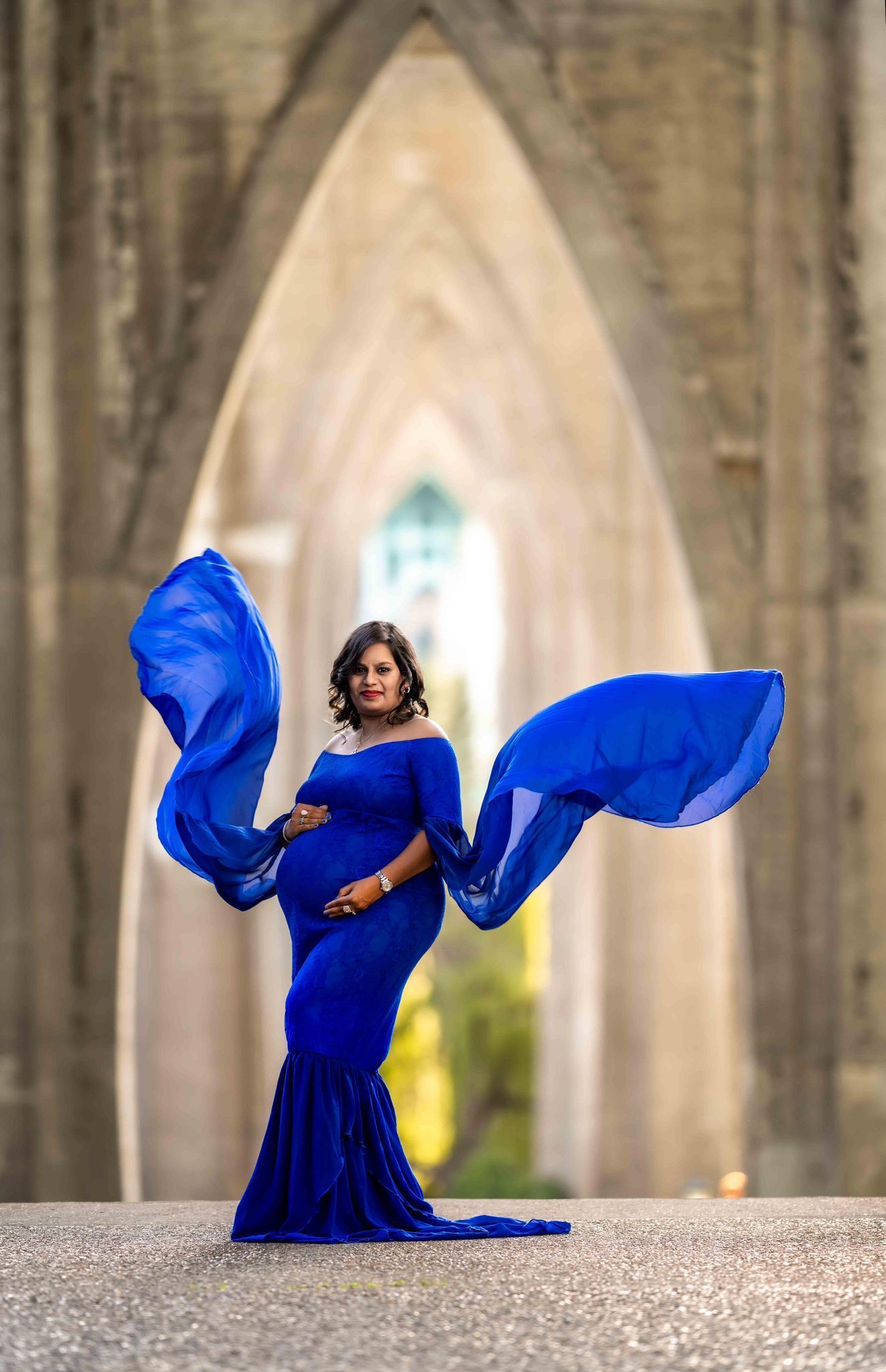 A pregnant woman in a blue dress is standing in front of a building