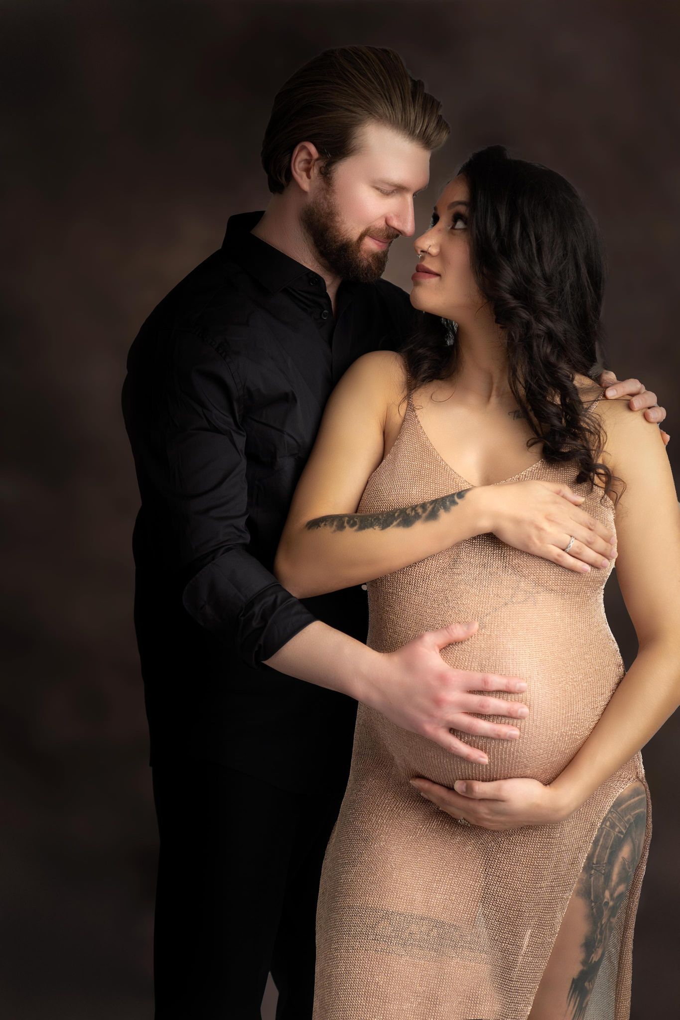 A man is hugging a pregnant woman in a sheer dress