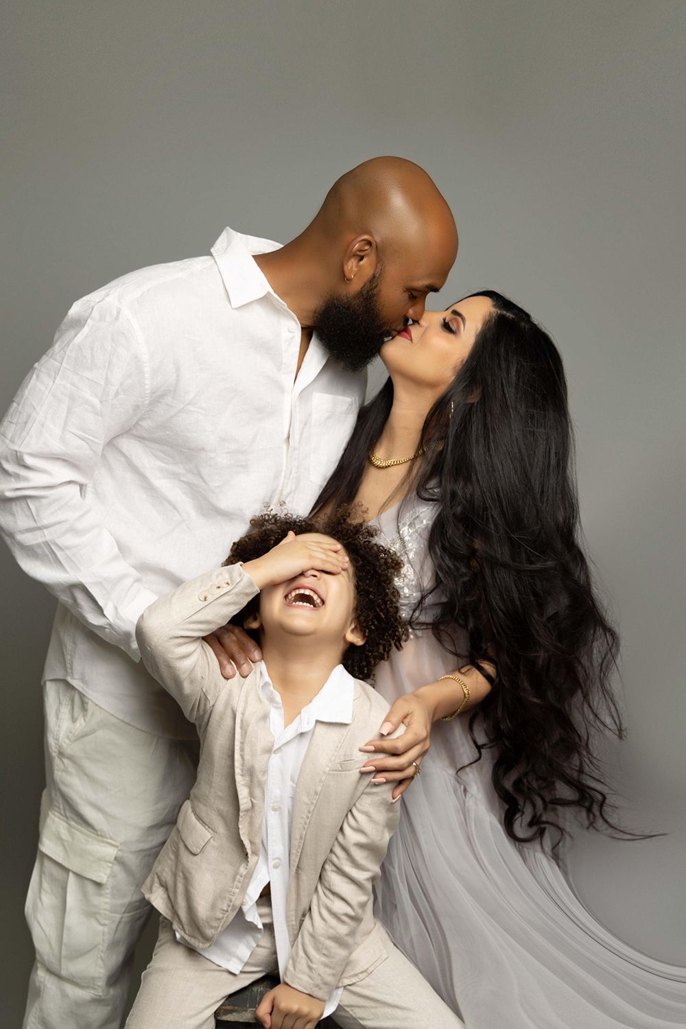 A man and a woman are kissing while their son is covering his eyes