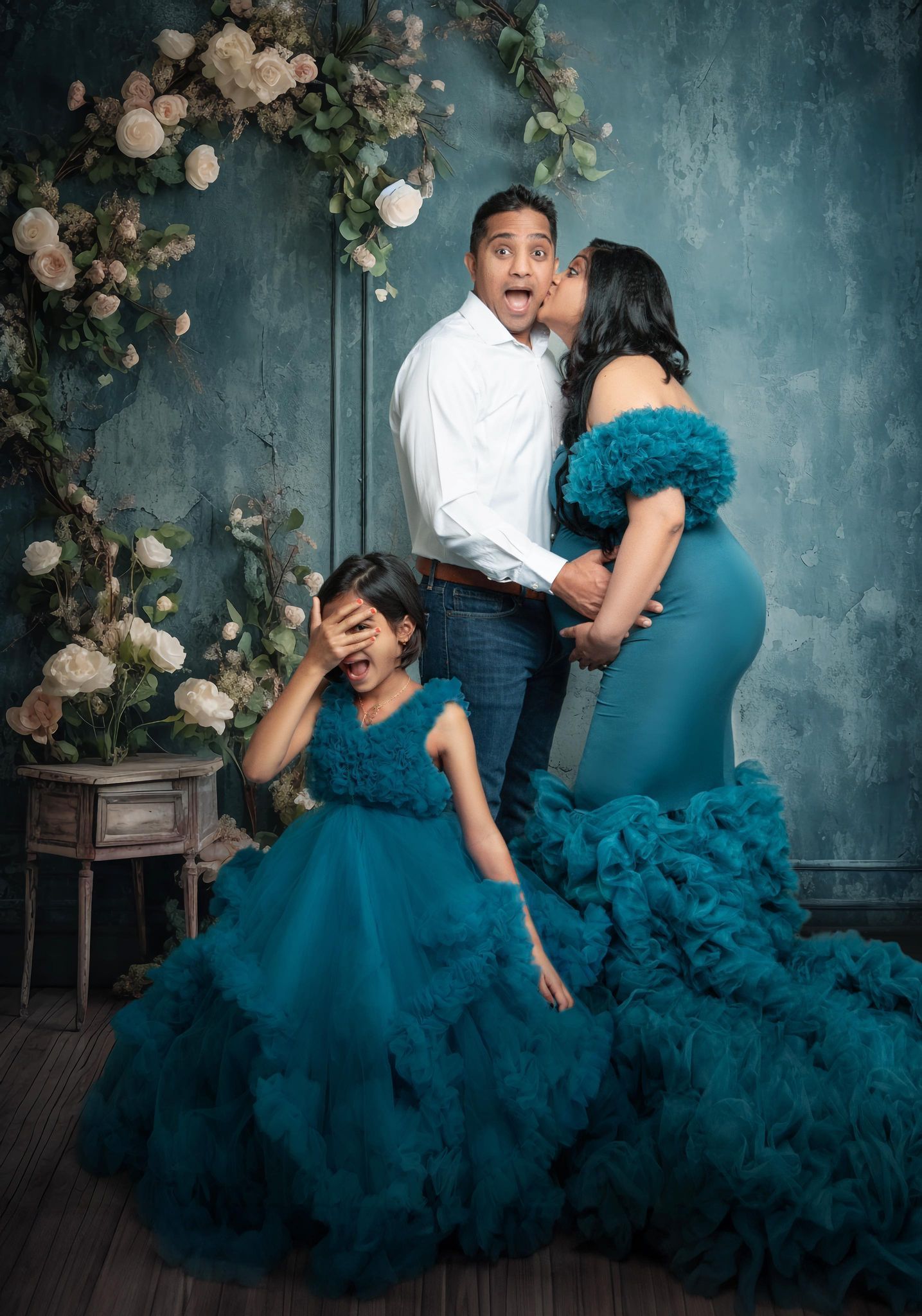 A woman is kissing a man on the cheek while standing next to their child