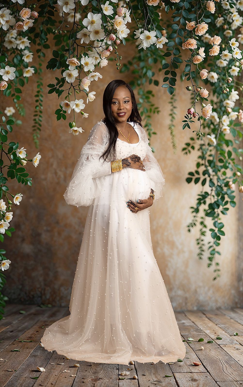 A pregnant woman is wearing a white dress and holding her belly