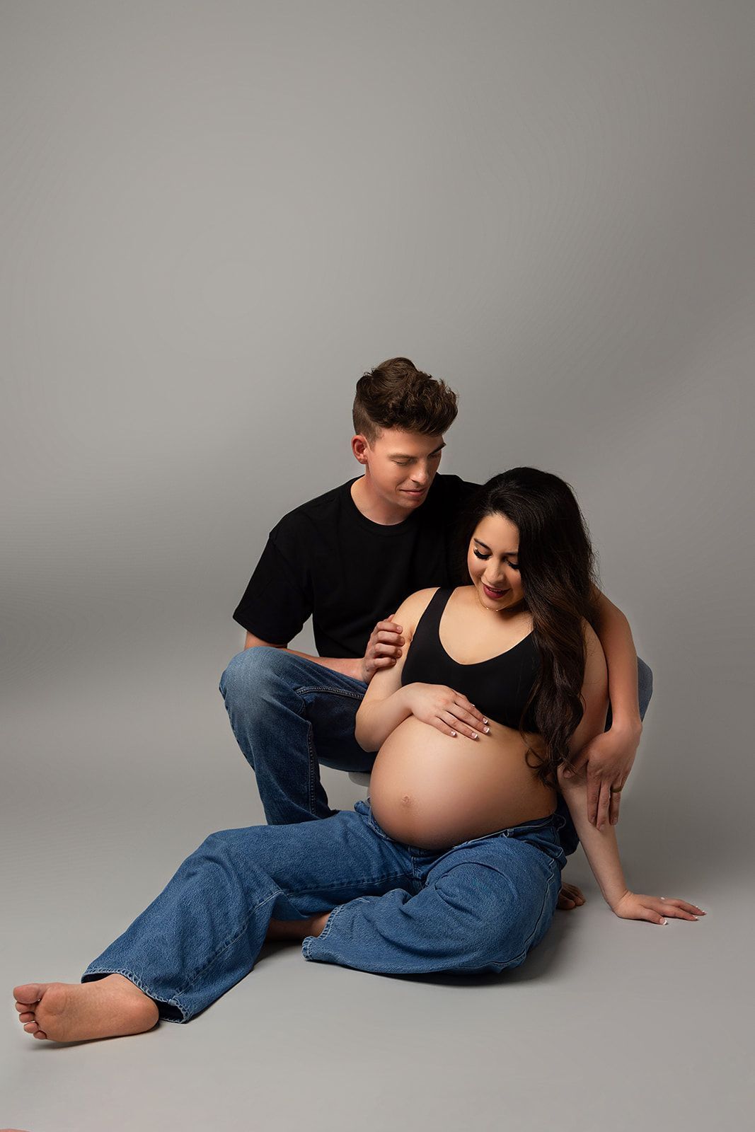 A pregnant woman is sitting on the floor next to her partner