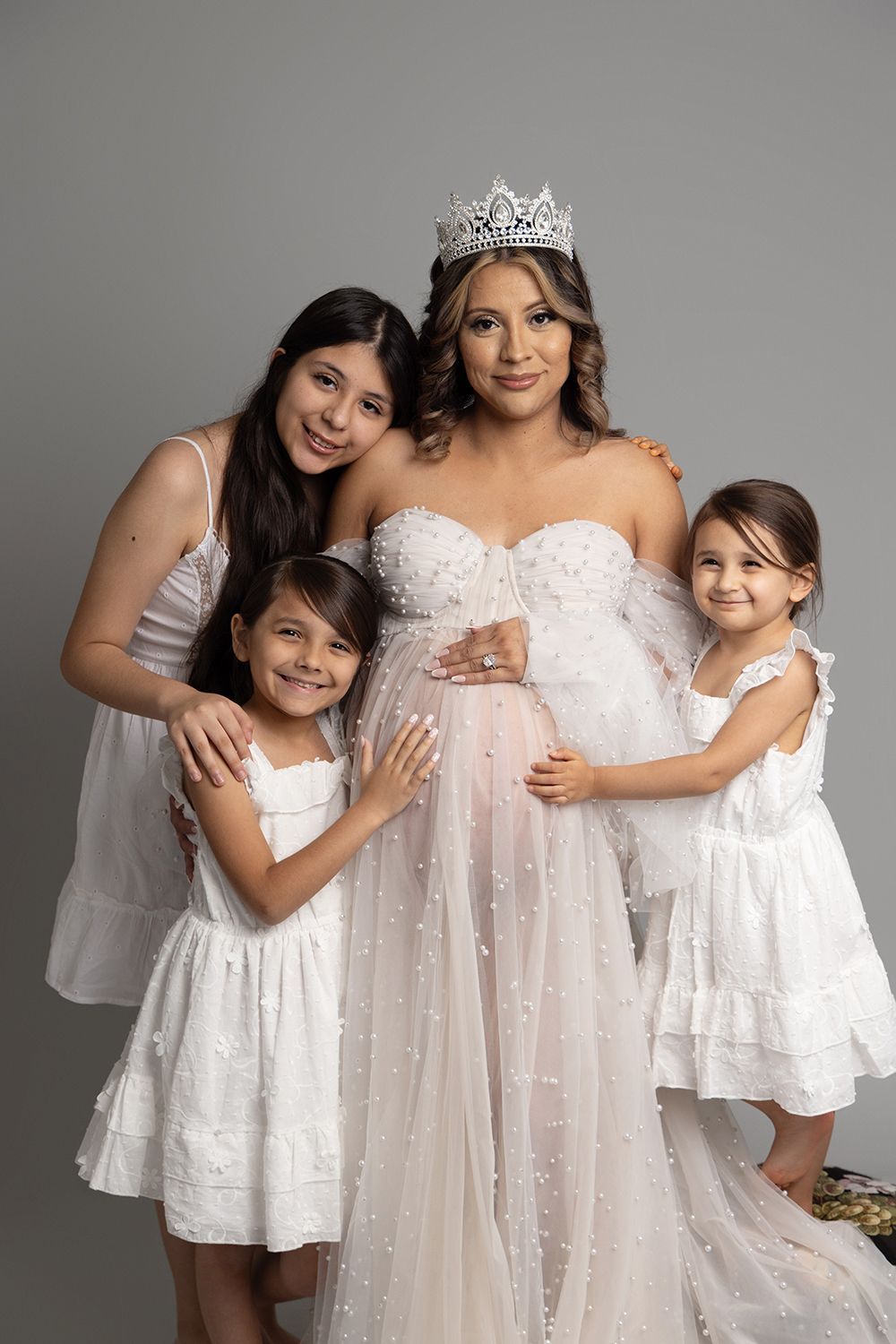 A pregnant woman is posing for a picture with three little girls