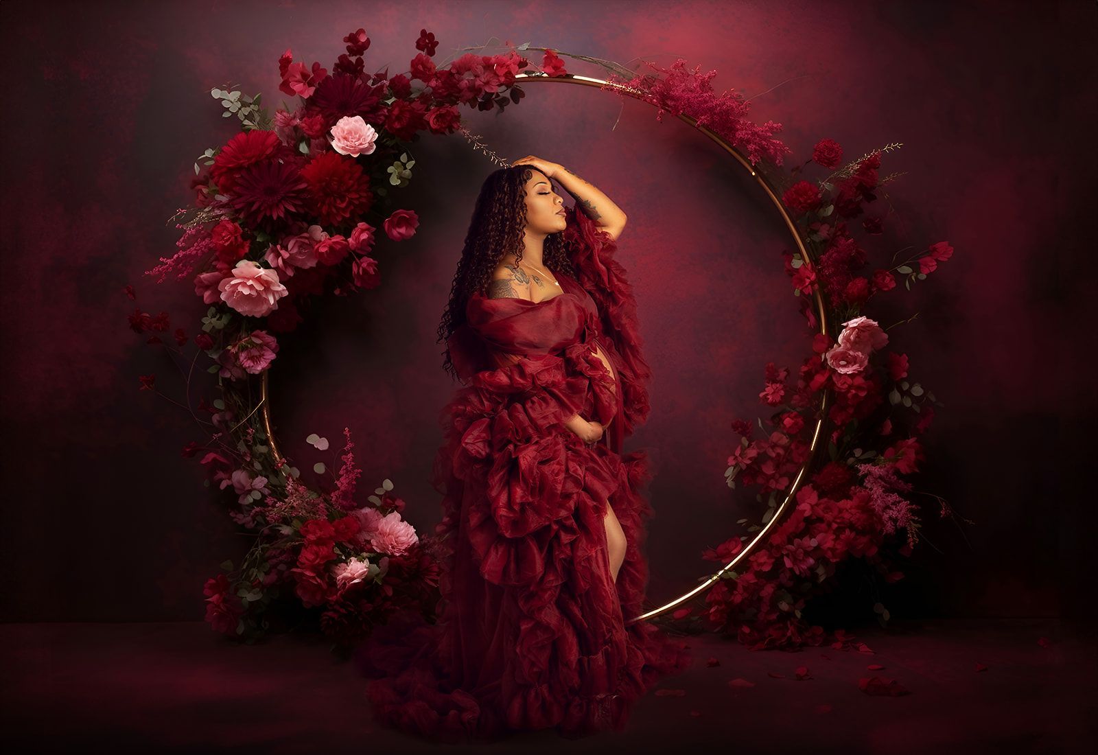 A pregnant woman in a red dress is standing in front of a floral background