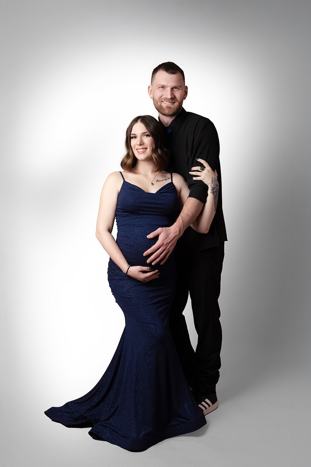 A man and a pregnant woman are posing for a picture