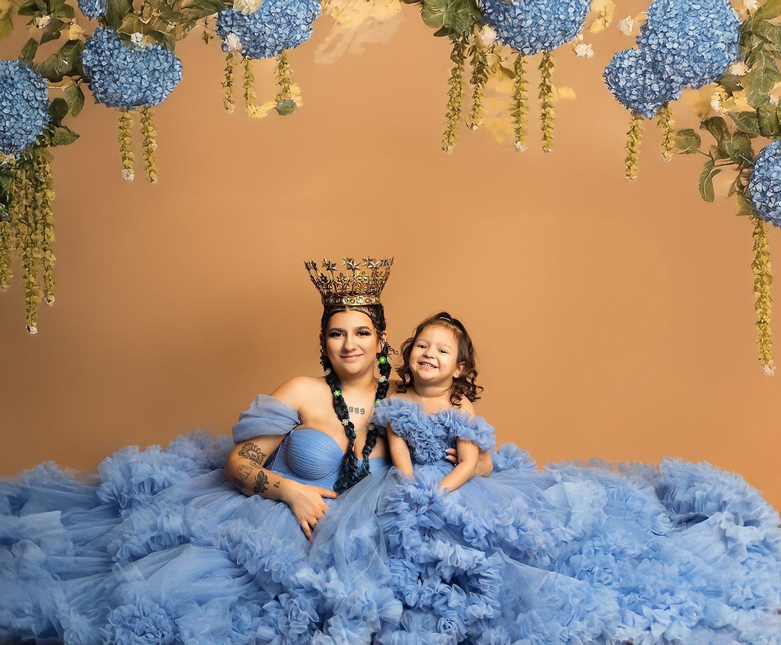 A woman and a little girl are wearing blue dresses and crowns.