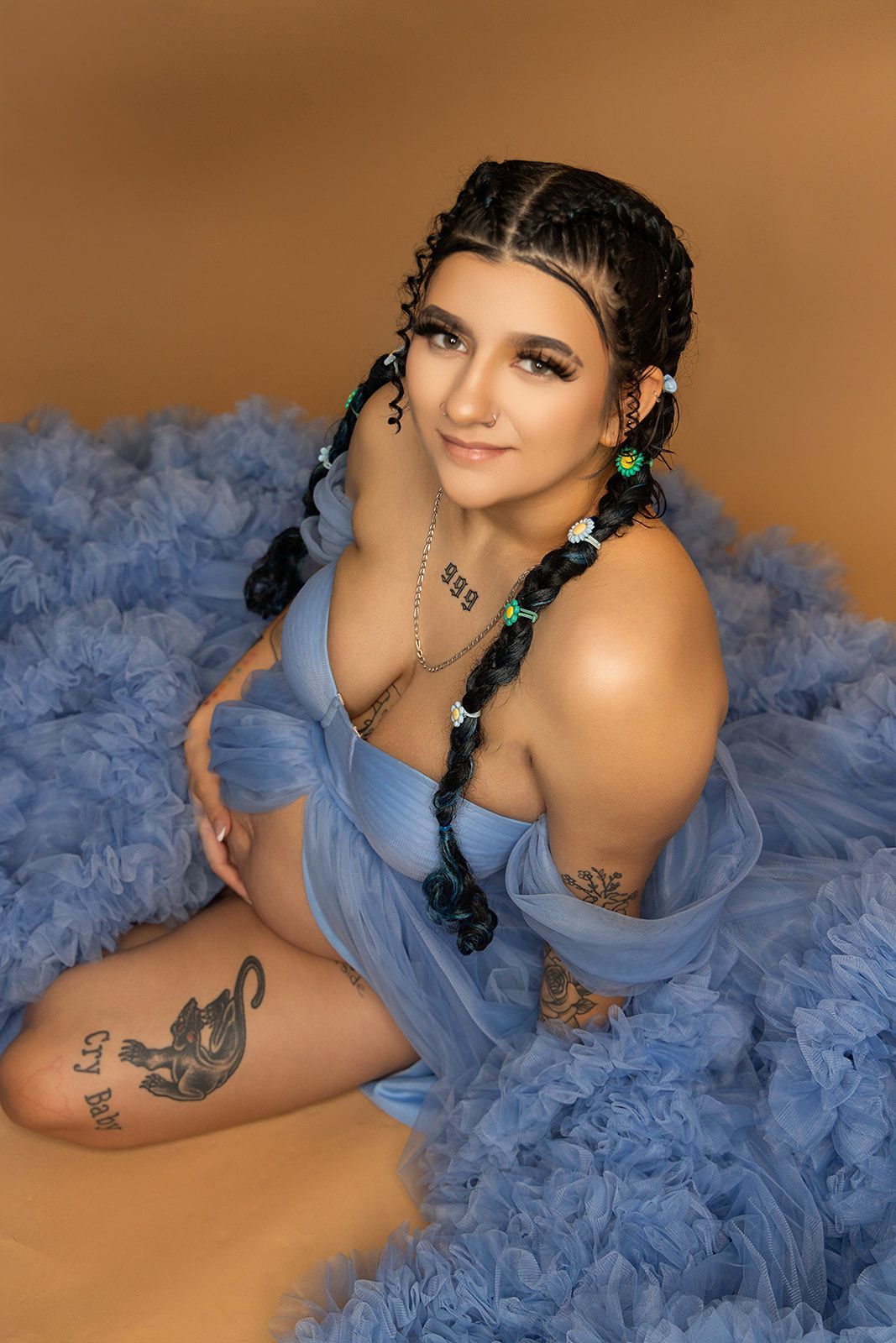 A pregnant woman in a blue dress is sitting on the floor.