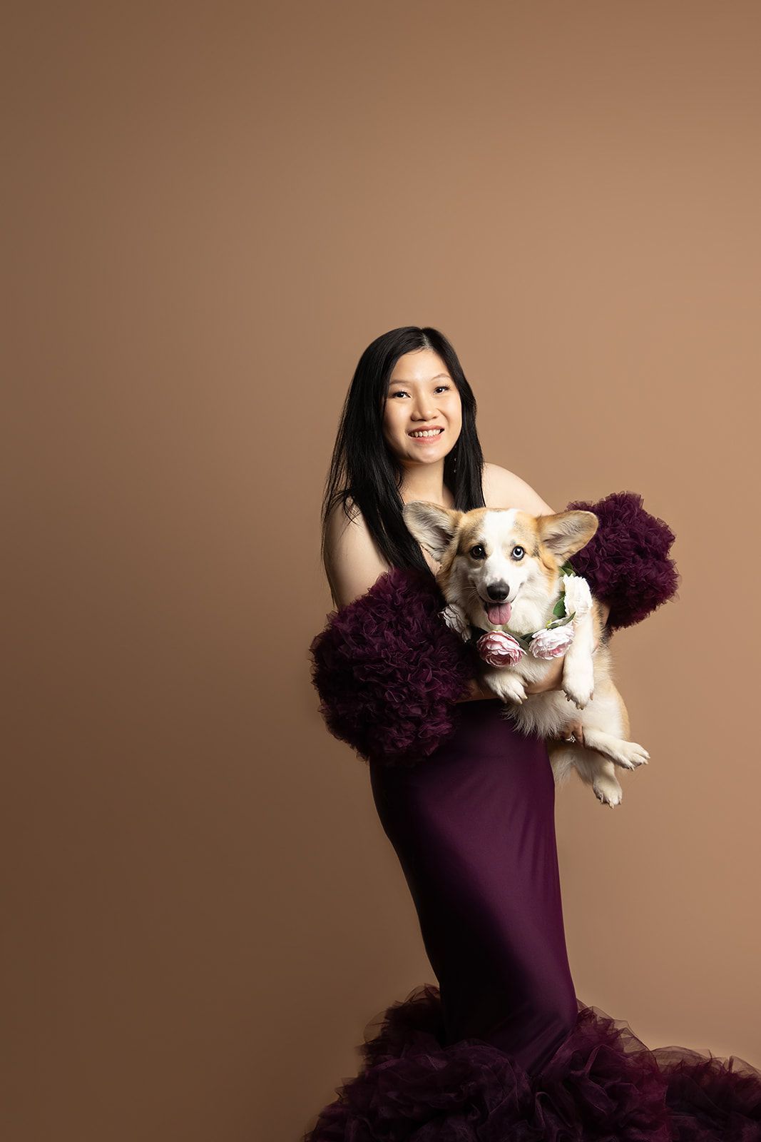 A woman in a purple dress is holding a dog.
