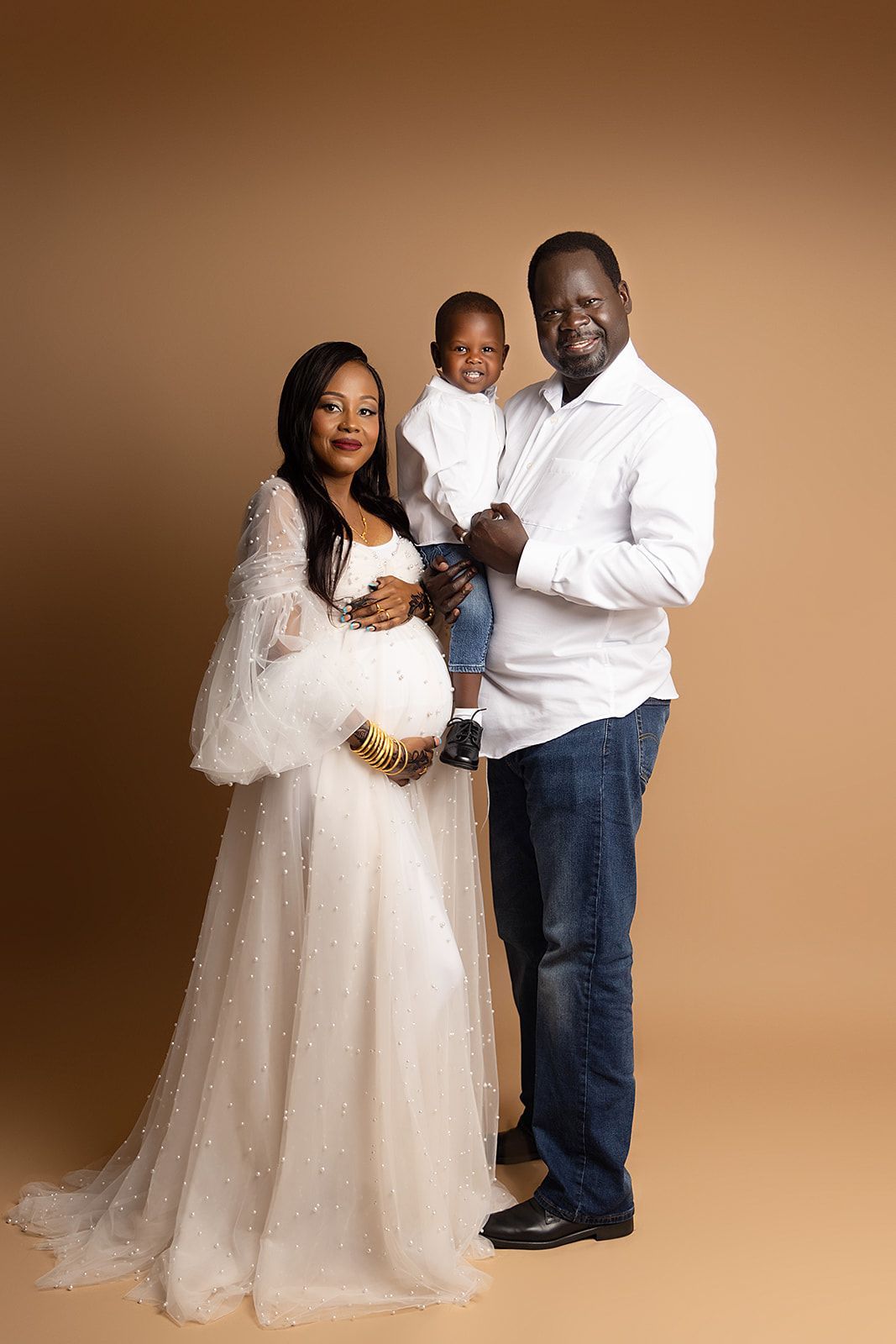 A pregnant woman is posing for a picture with her husband and son.