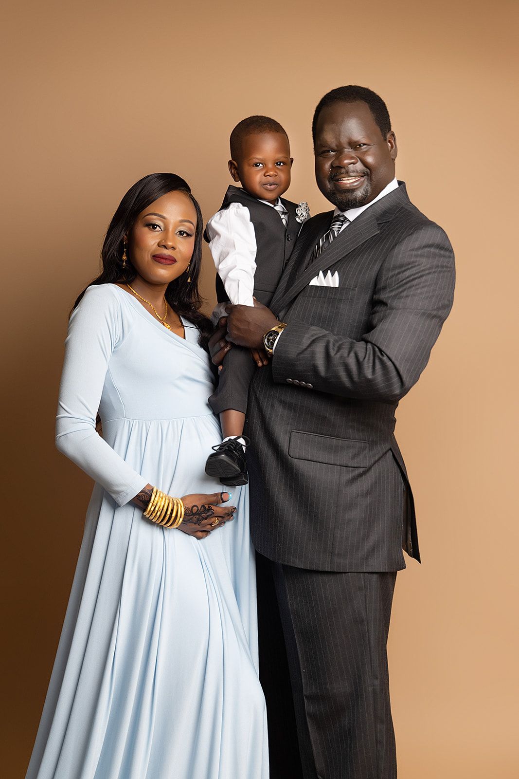 A pregnant woman is standing next to a man and a child.