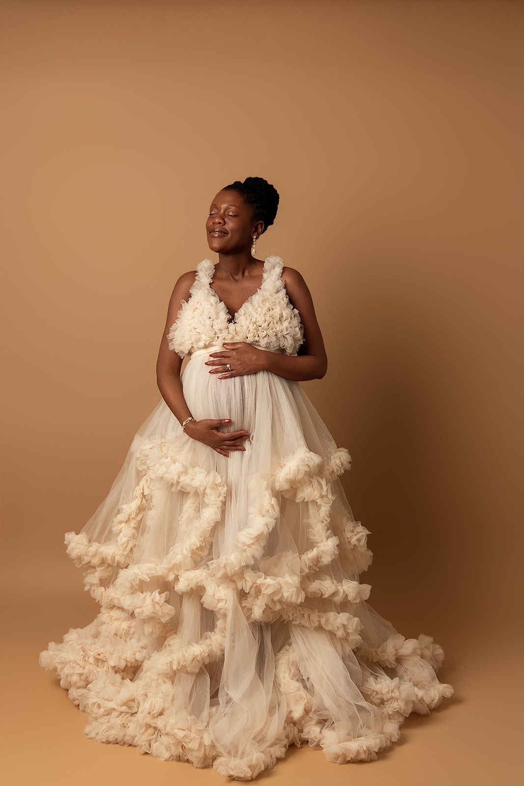 A pregnant woman in a white dress is holding her belly.