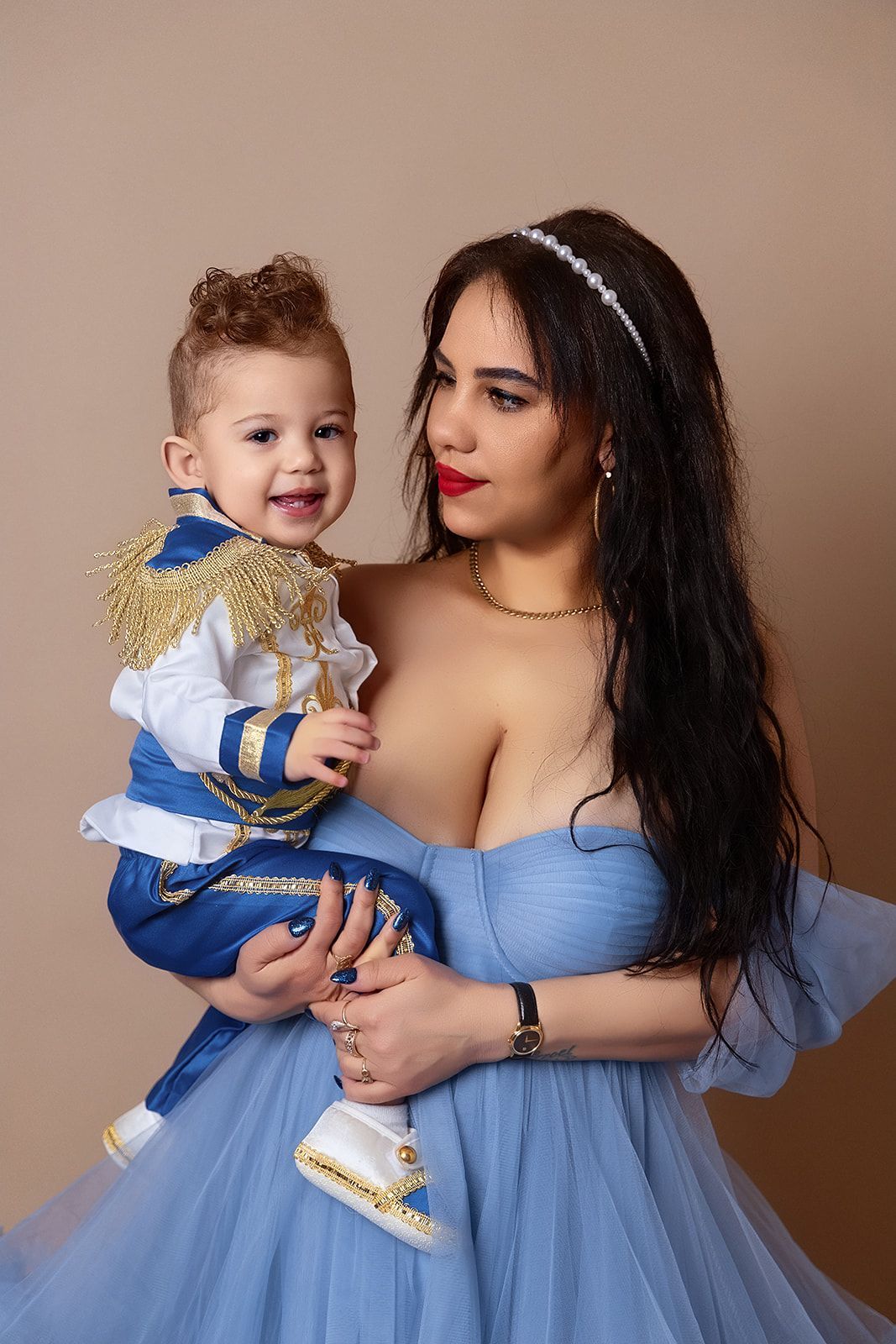 A woman in a blue dress is holding a baby in her arms.