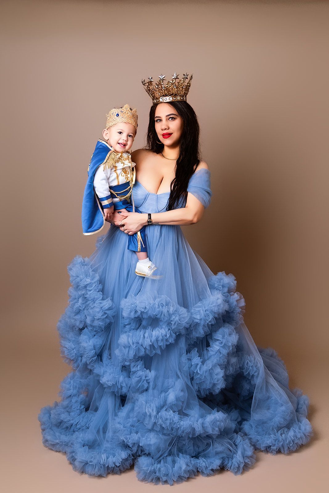 A woman in a blue dress is holding a baby in her arms.