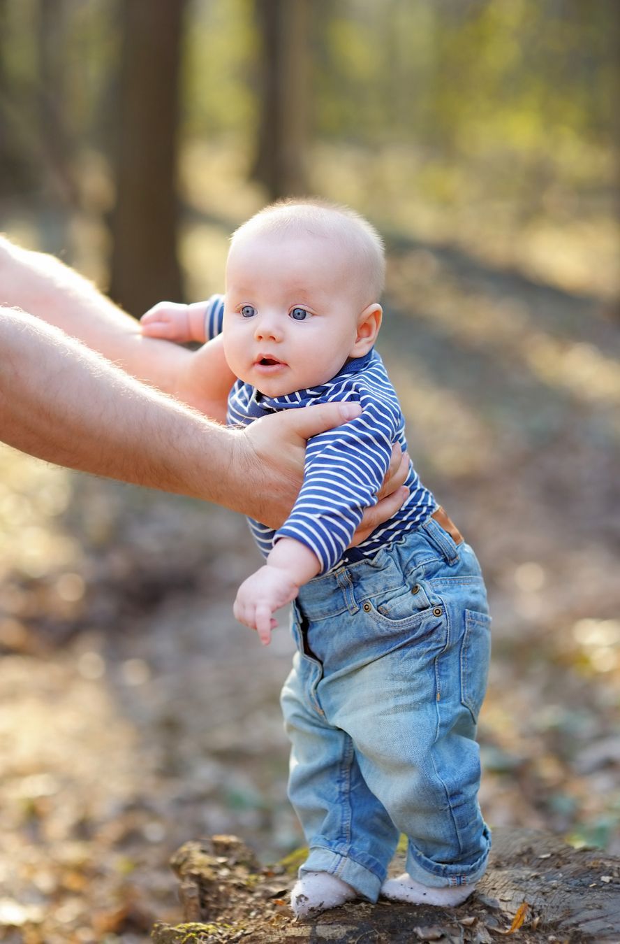 A baby is being held by a person in the woods