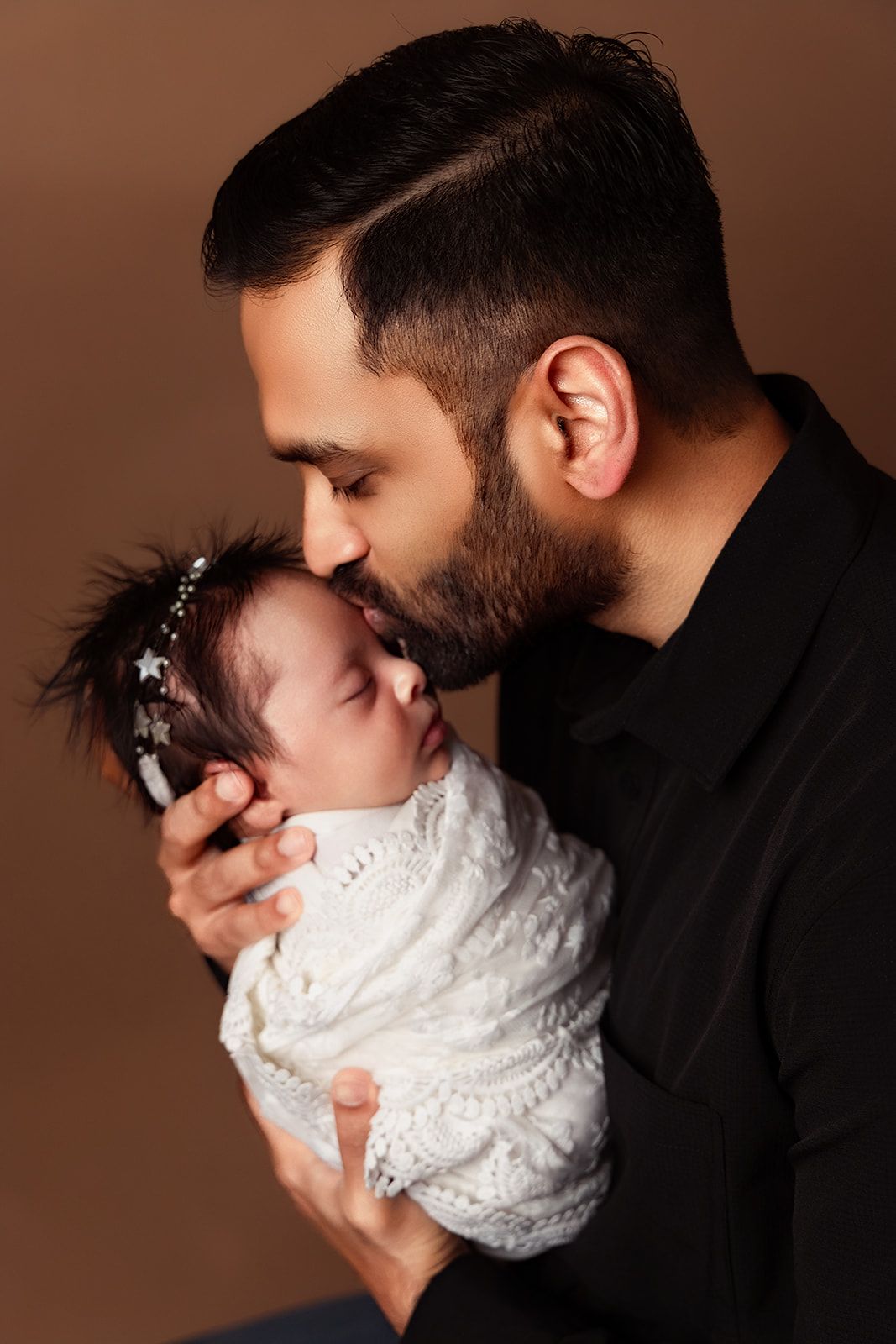 A man is kissing a baby on the cheek.