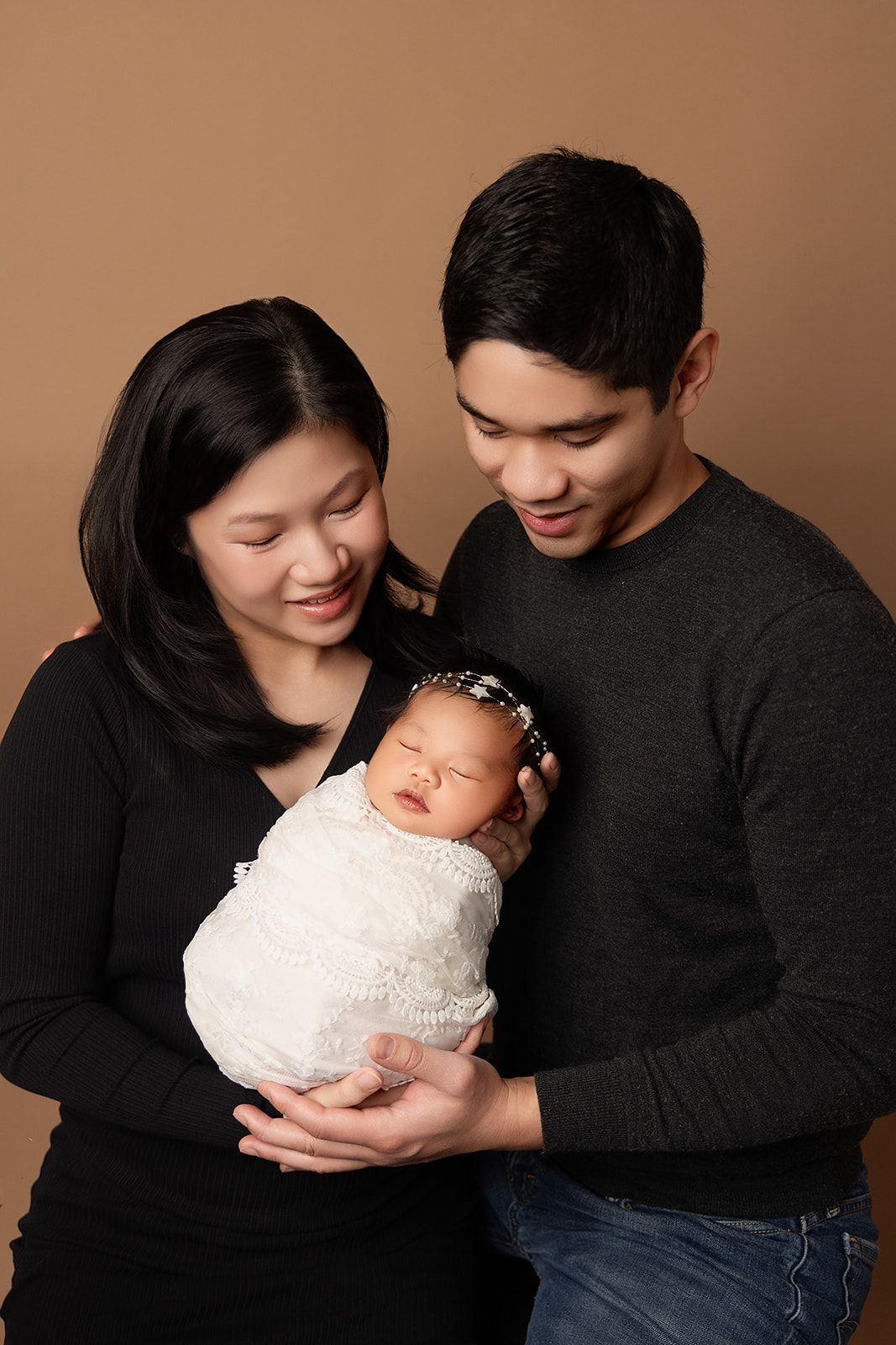 A man and woman are holding a newborn baby in their arms.