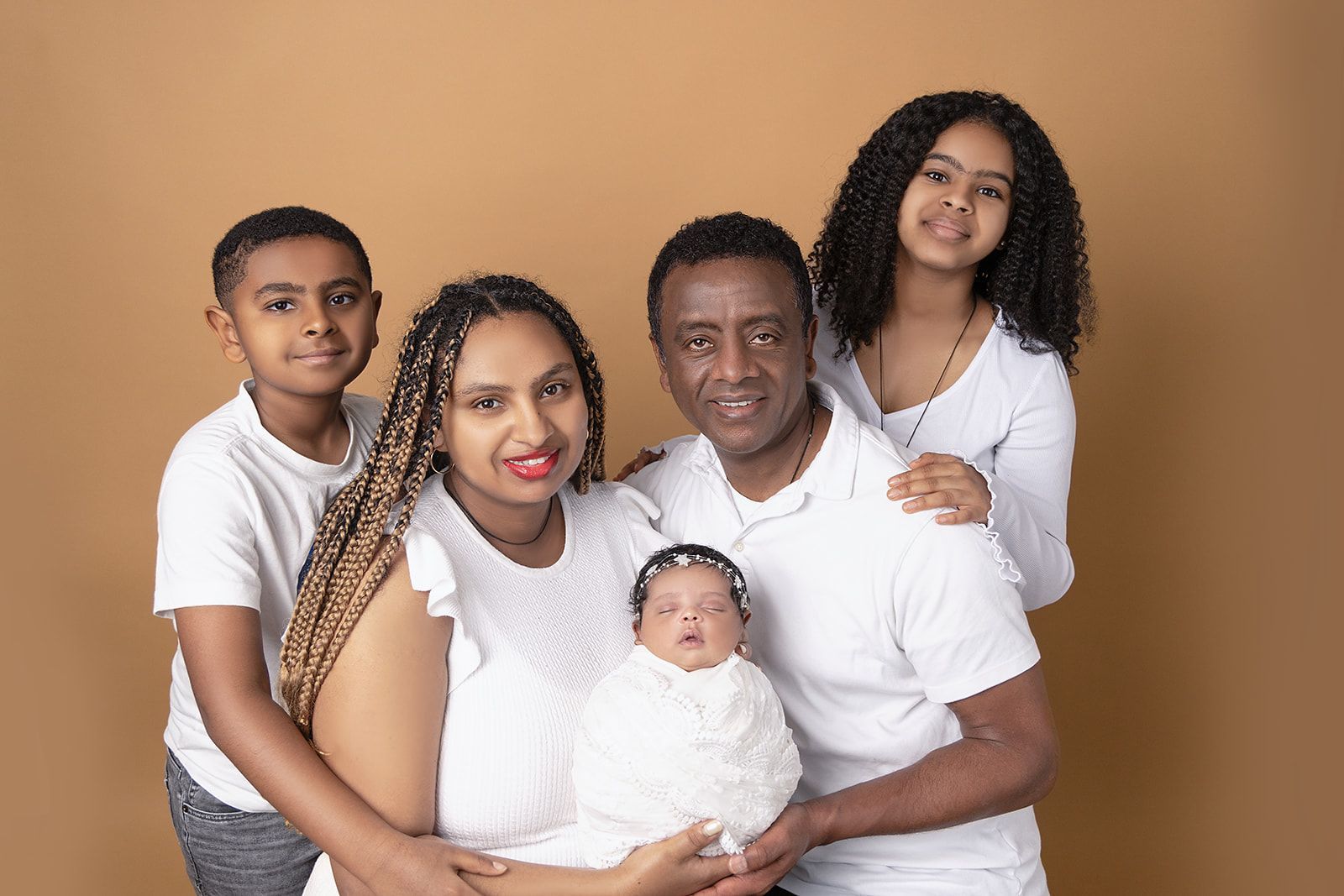 A family is posing for a picture with a newborn baby.