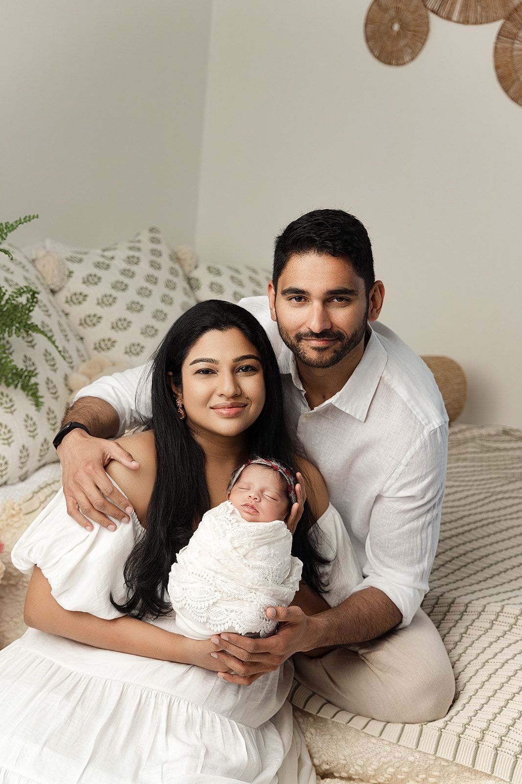 A man and woman are posing for a picture with their newborn baby.