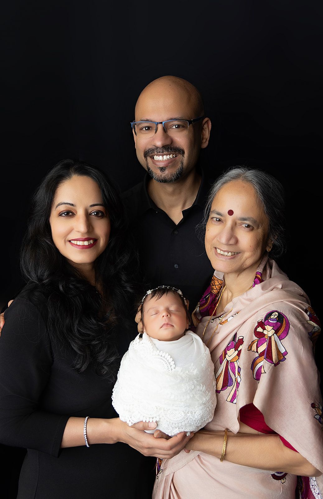 A family is posing for a picture with a newborn baby.