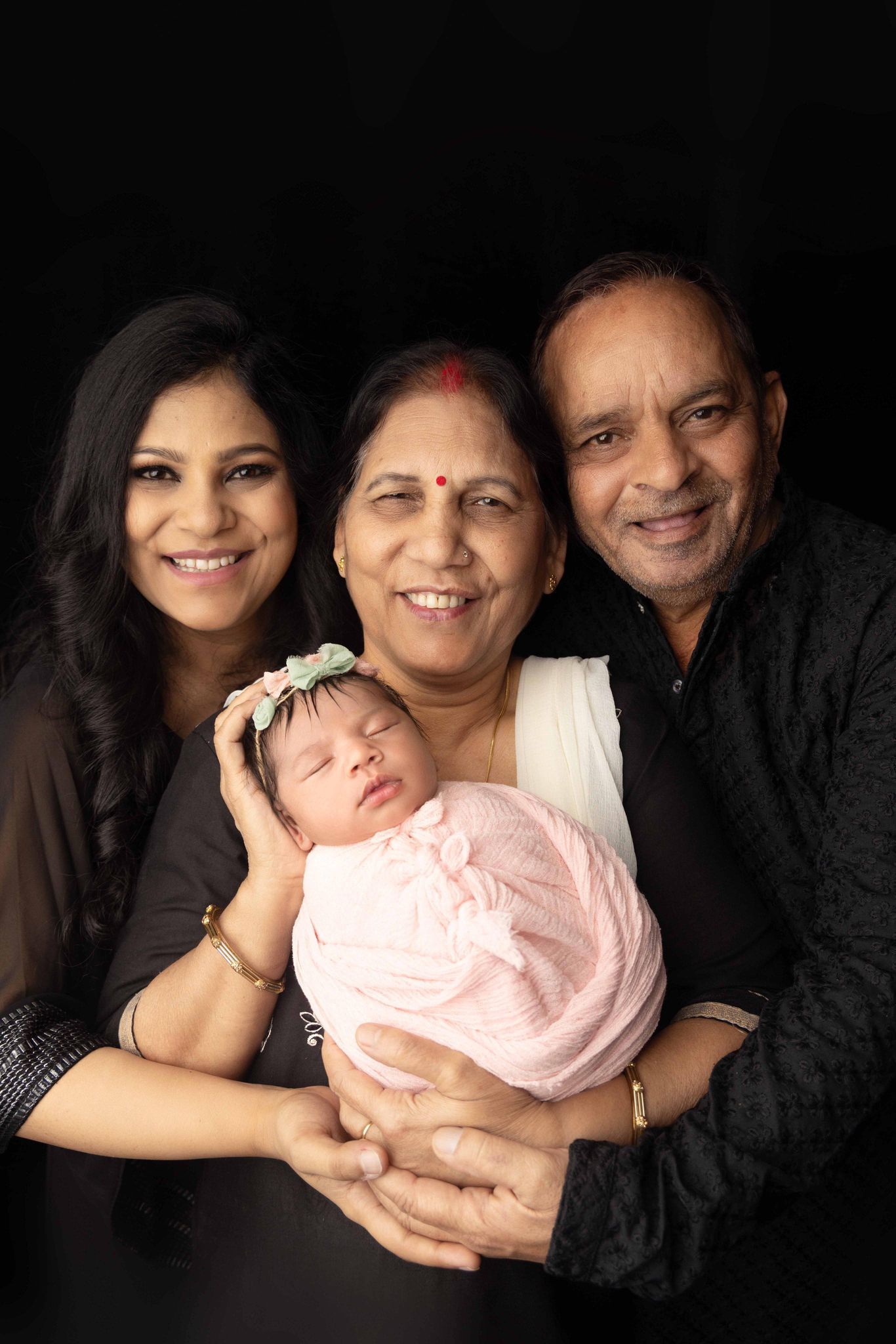 A family is posing for a picture with a newborn baby.