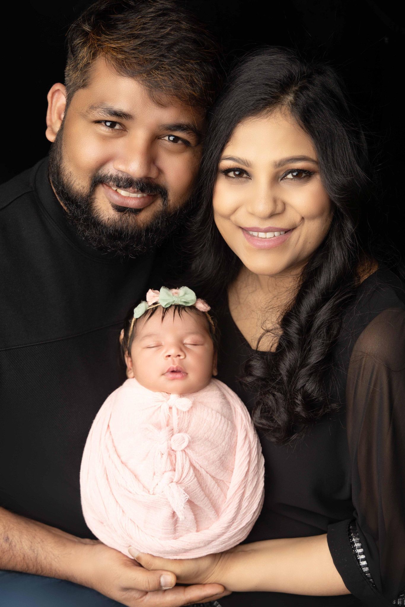 A man and woman are holding a newborn baby in their arms.