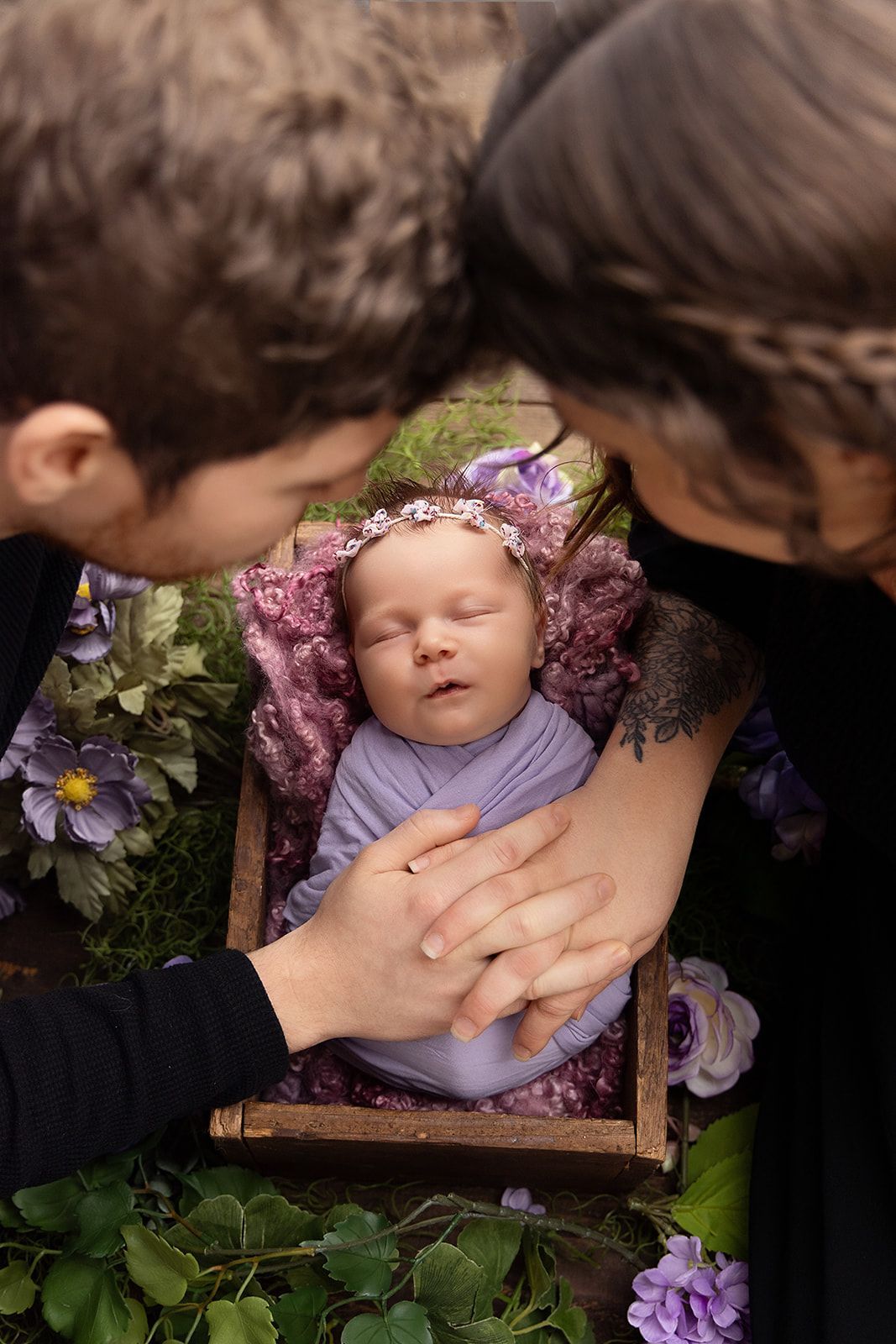 A family is holding a newborn baby in a wooden crate.