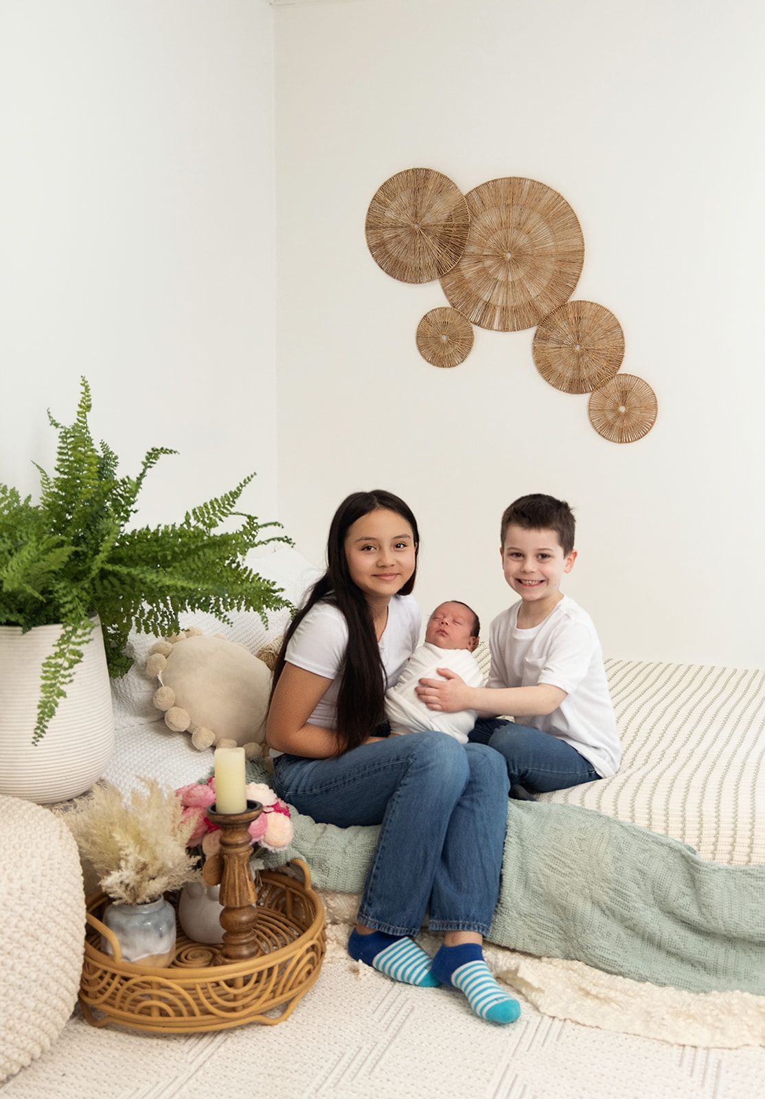 A woman and two children are sitting on a bed holding a newborn baby.