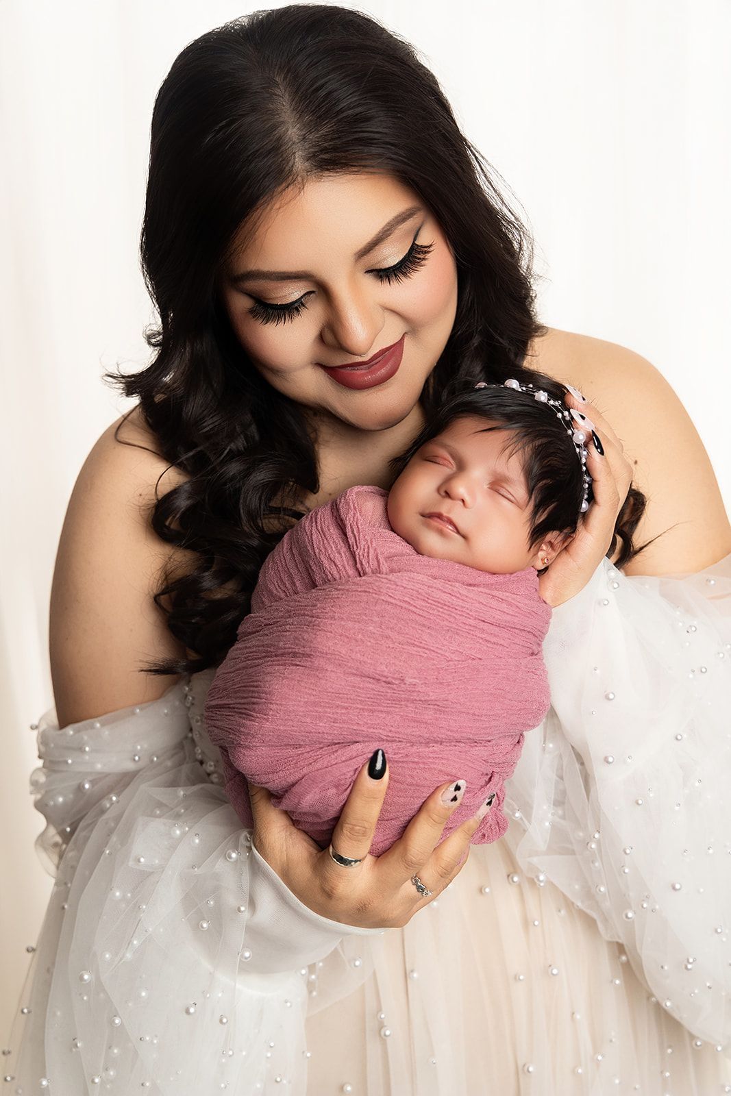 A woman is holding a newborn baby wrapped in a pink blanket.