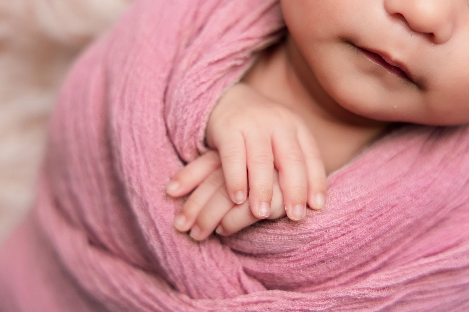 A close up of a baby wrapped in a pink blanket.