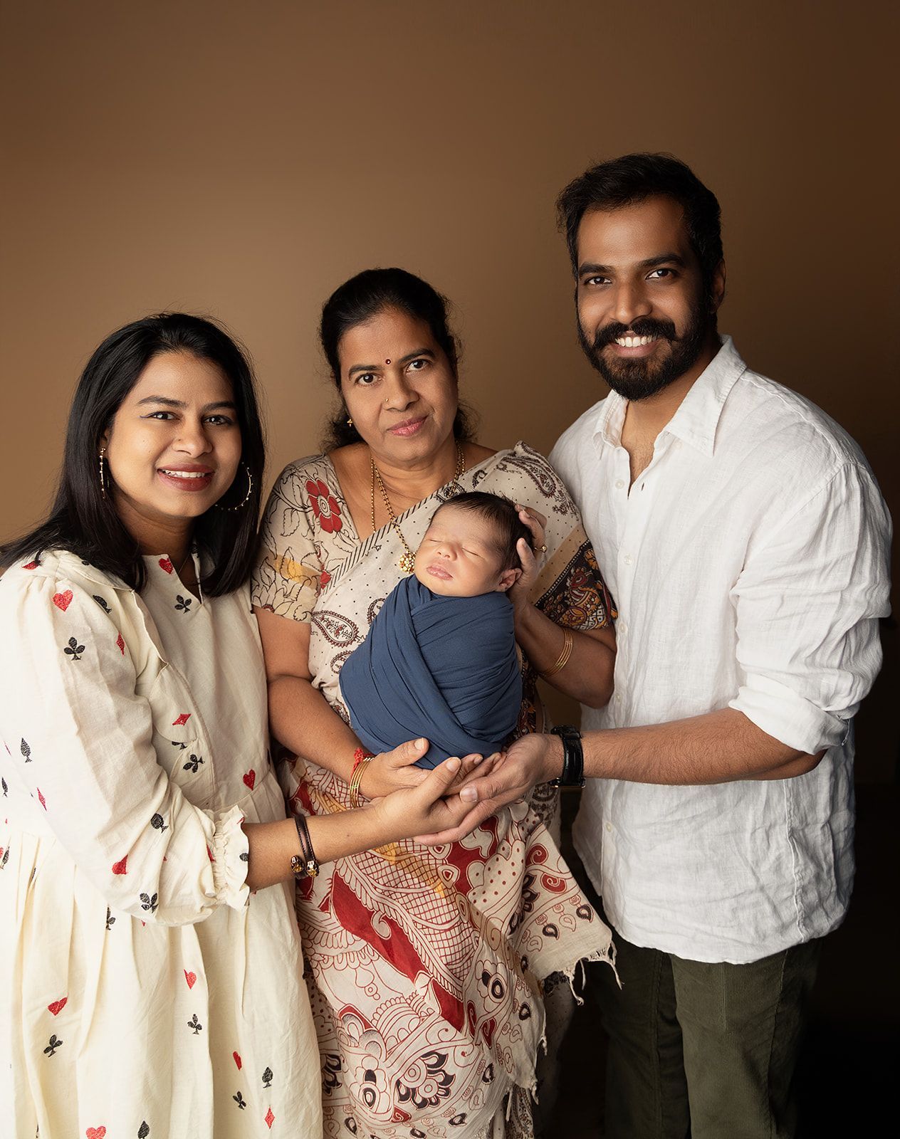 A family is posing for a picture with a newborn baby.