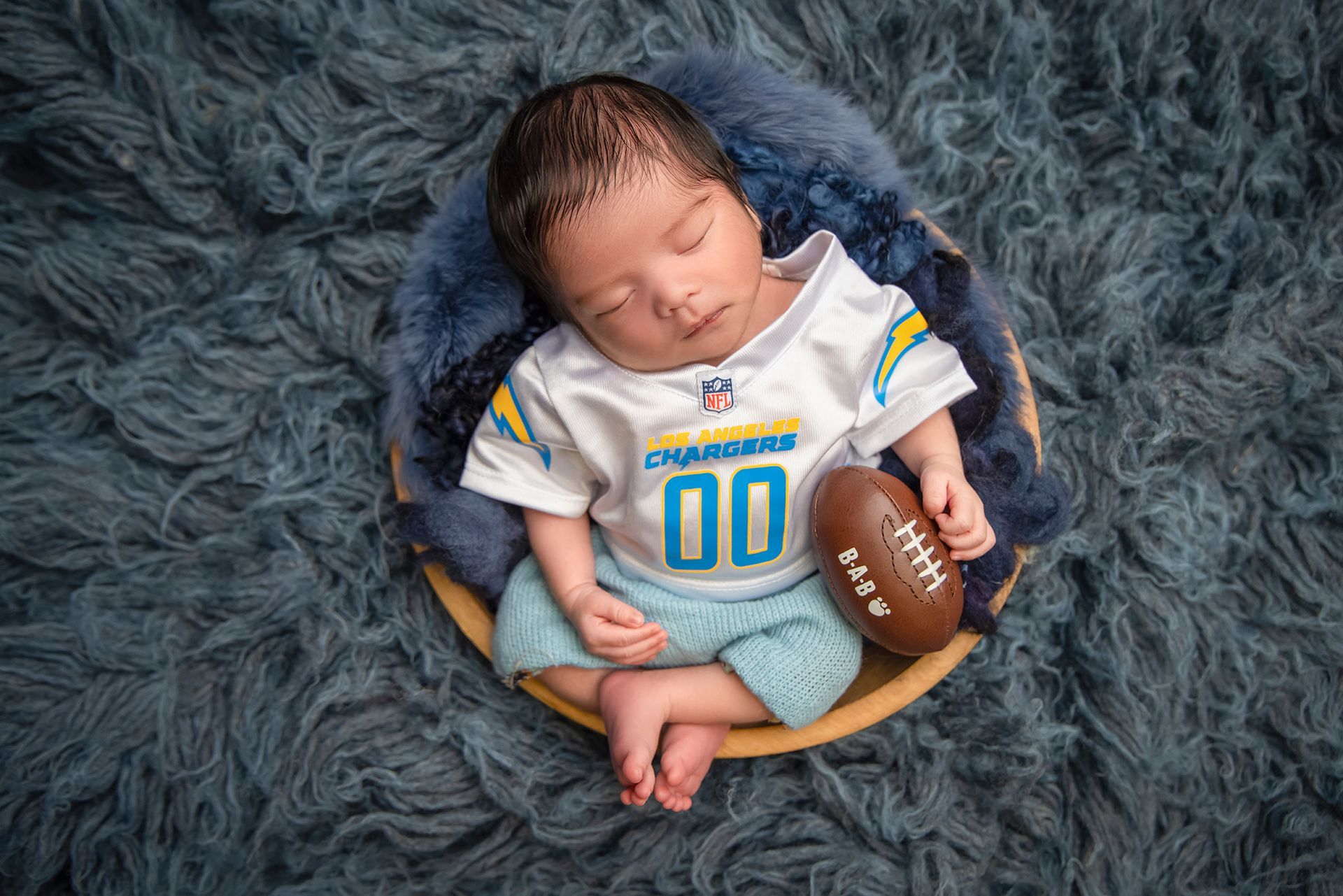 A newborn baby wearing a Los Angeles Chargers uniform