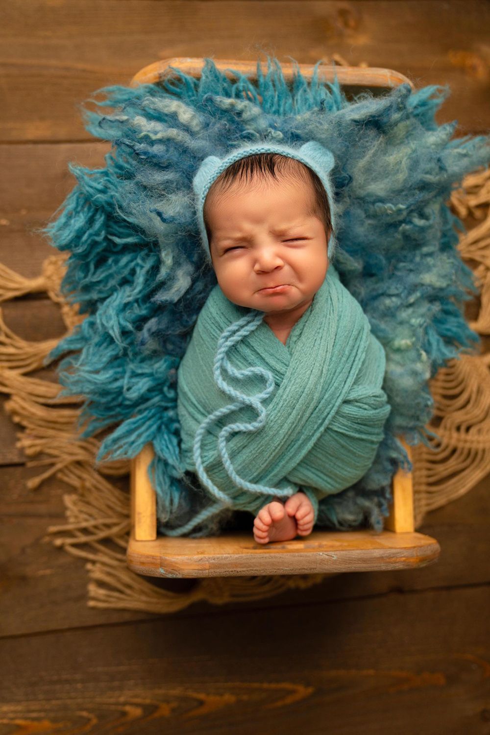 A crying newborn baby wrapped in a blue blanket
