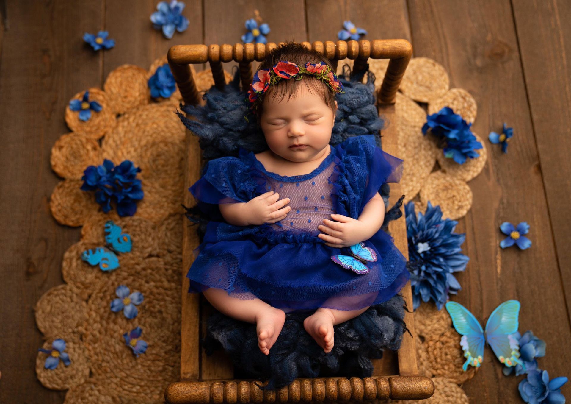 A baby in a blue dress is sleeping in a wooden bed