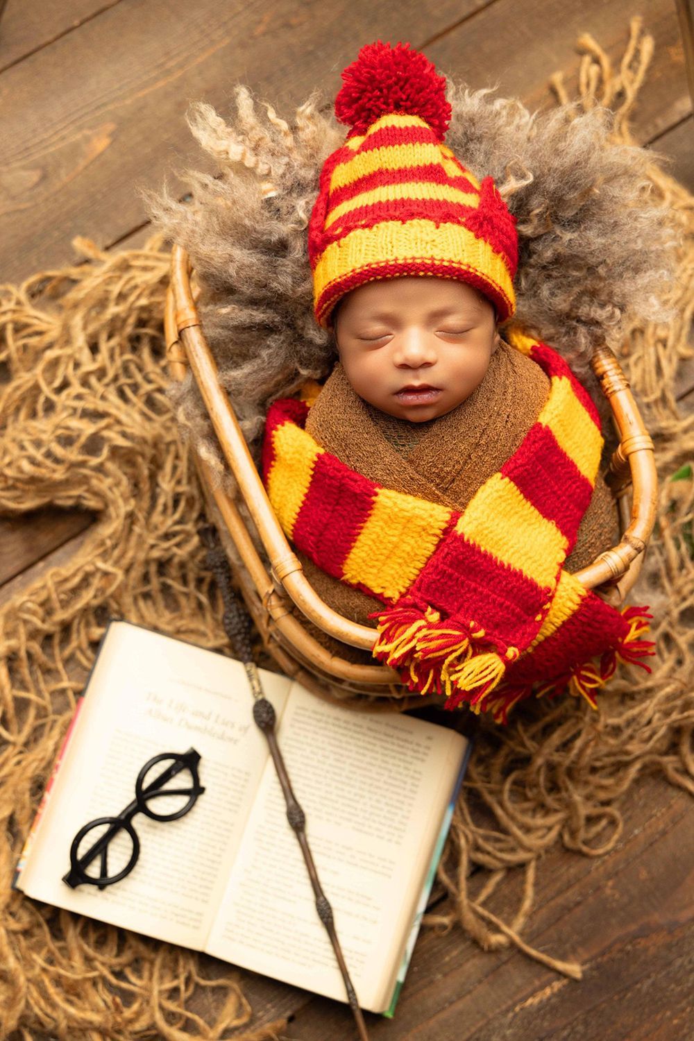 A newborn baby beside a Harry Potter book, Harry's glasses, and the Elder Wand