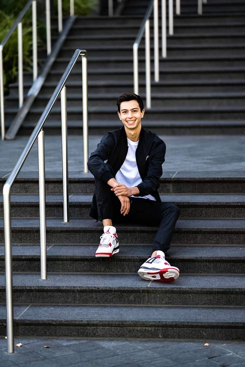 A young man is sitting on a set of stairs