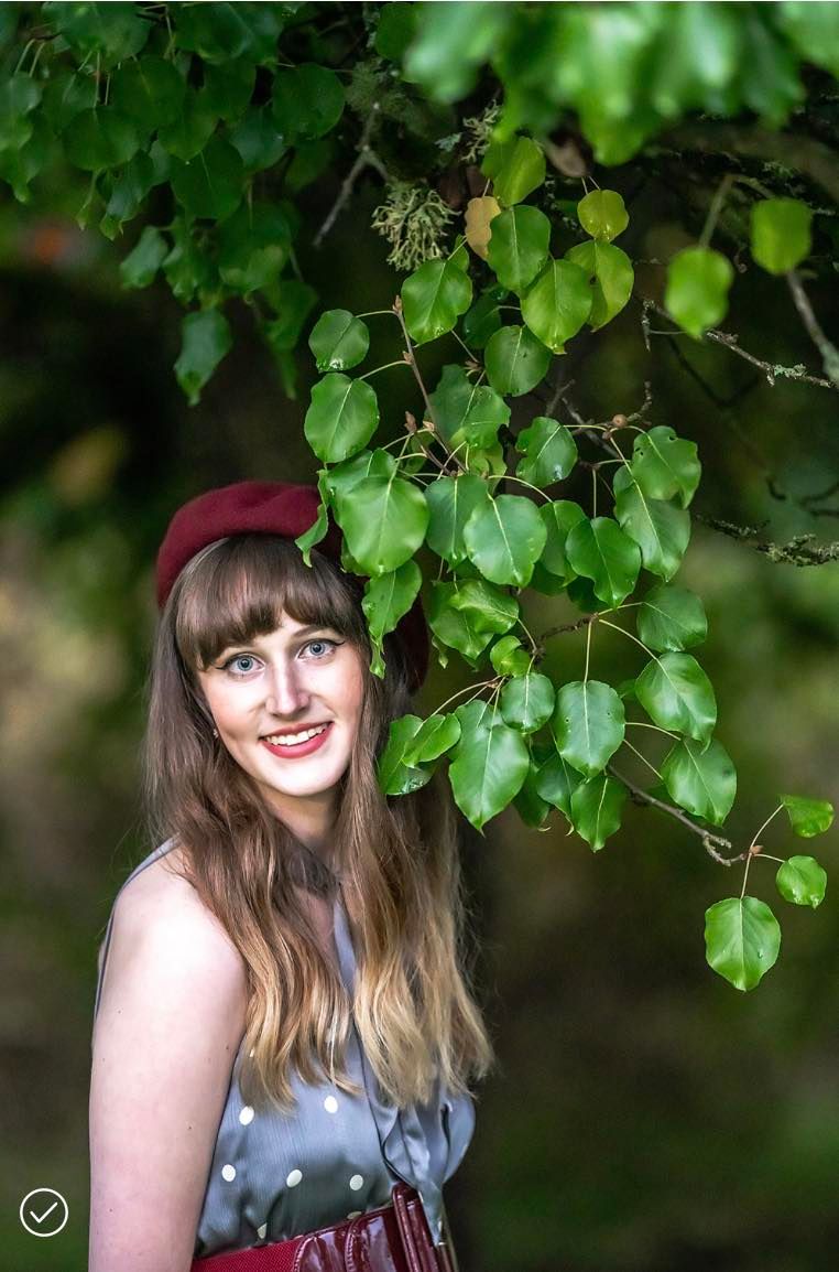 A woman in a red hat is standing under a tree
