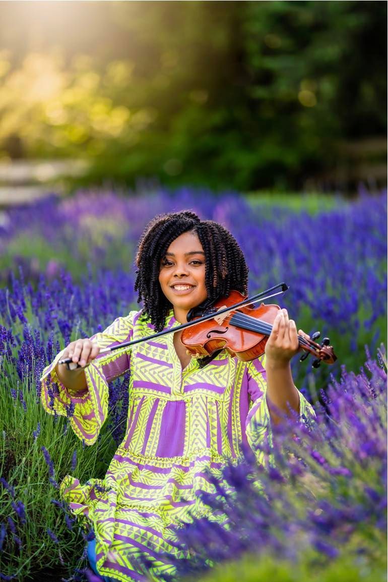 A young woman is playing a violin in a lavender field