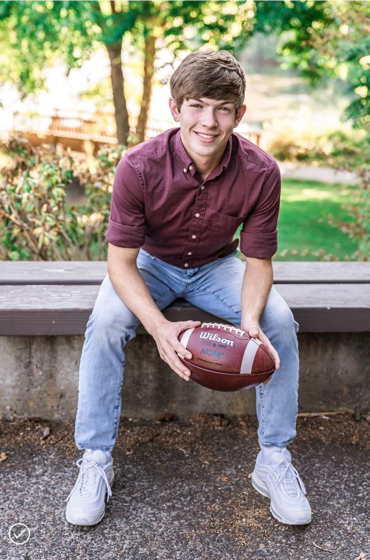 A young man is sitting on a bench holding a football