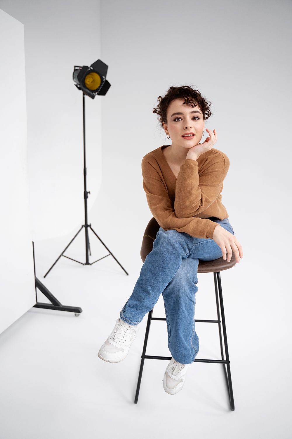 A woman is sitting on a stool in front of a light