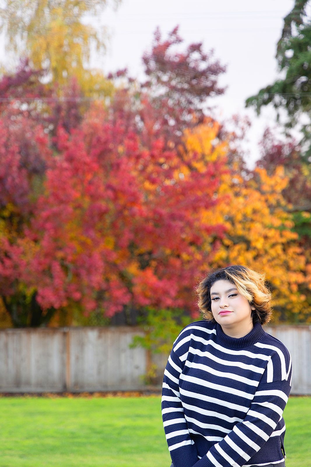 A woman in a striped sweater is standing in a park