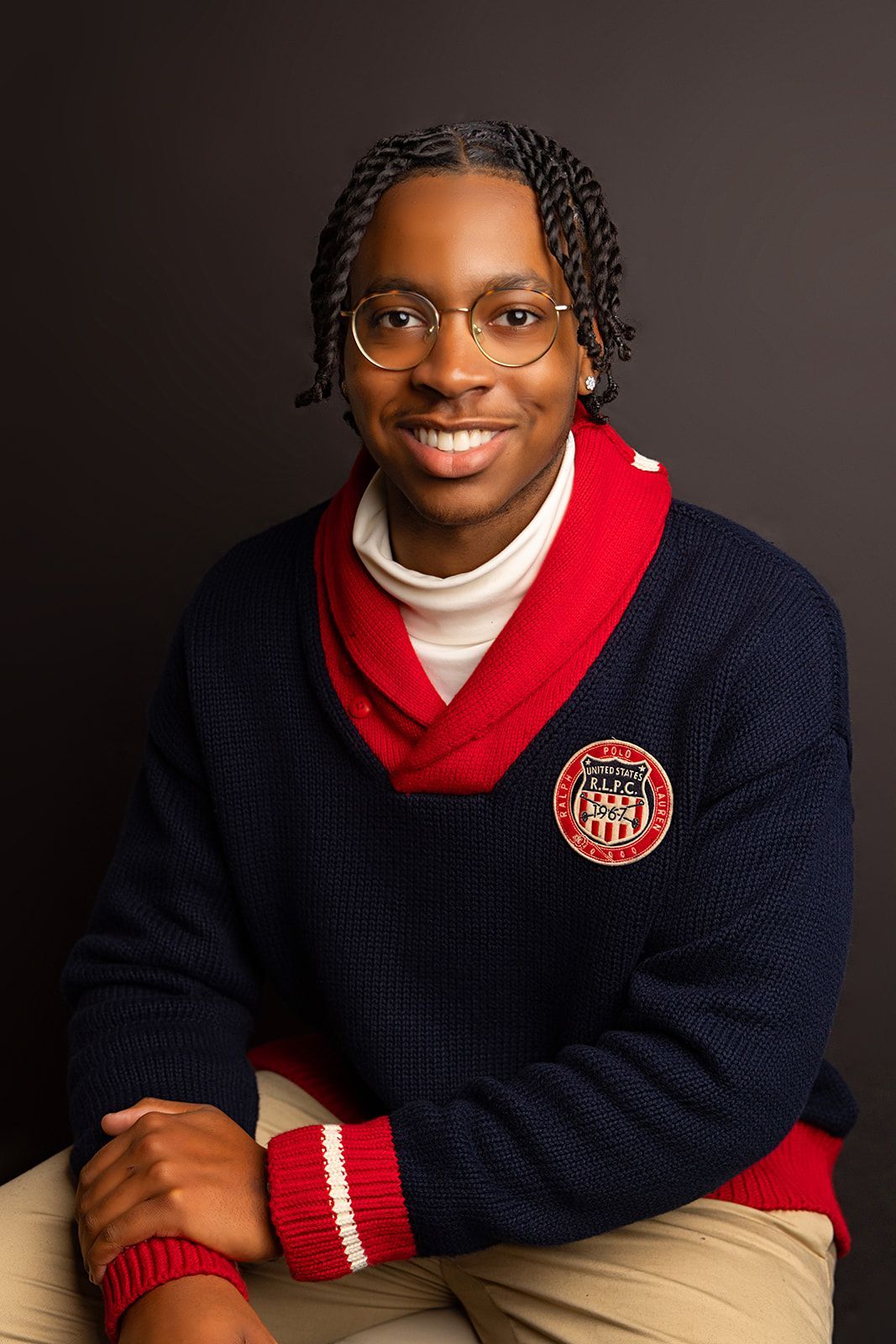 A young man wearing a sweater and glasses