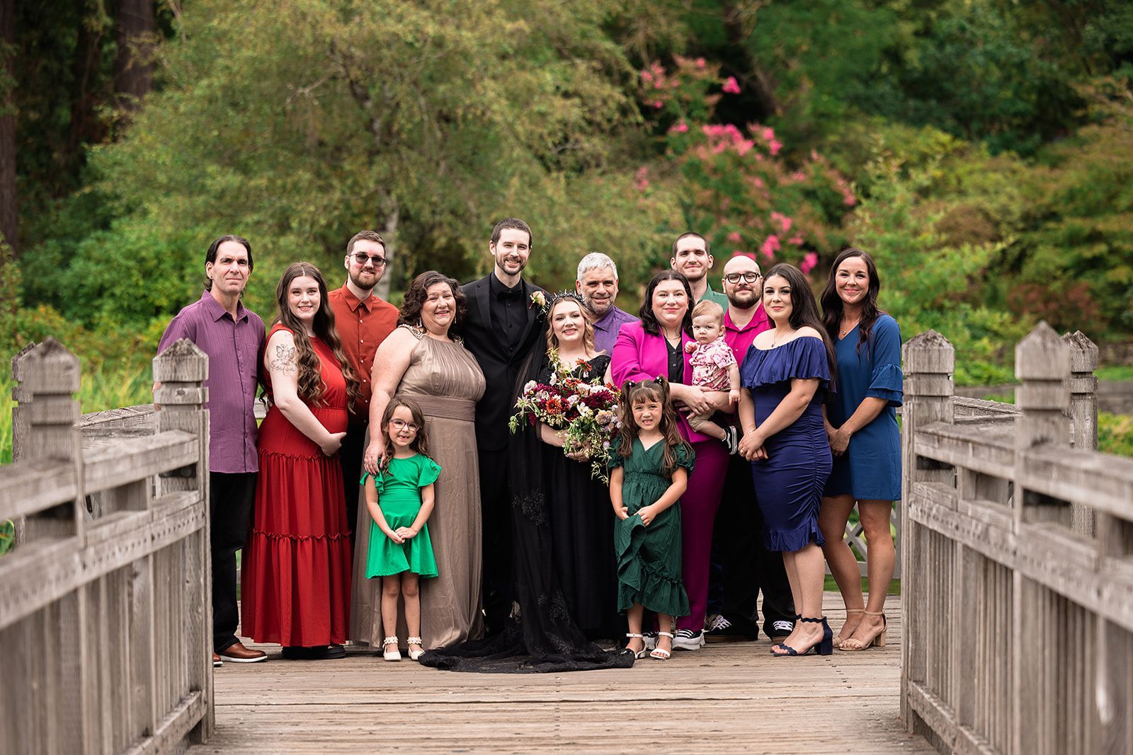 A large family is posing for a picture on a wooden bridge.