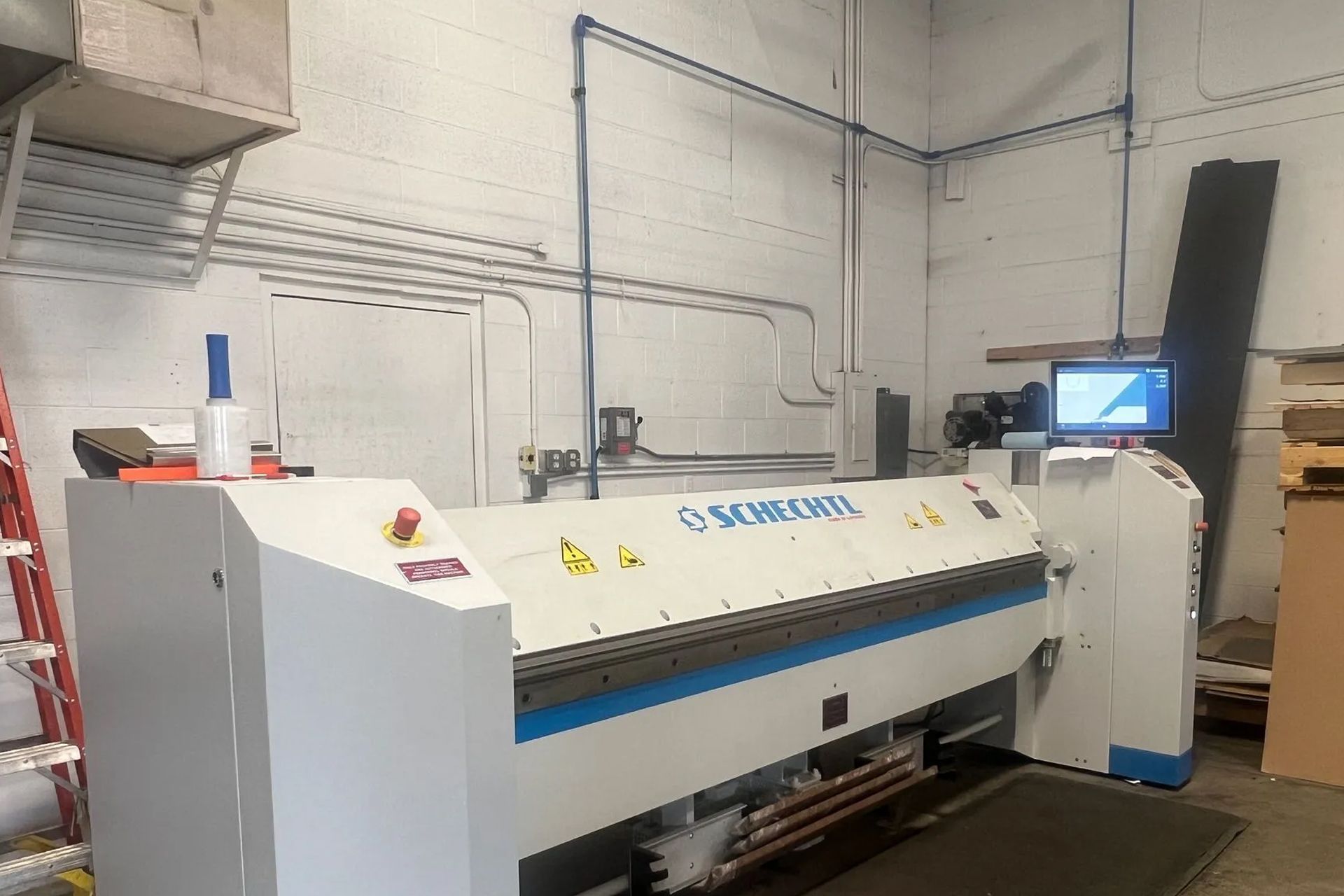 Large industrial metal bending machine in a warehouse setting.