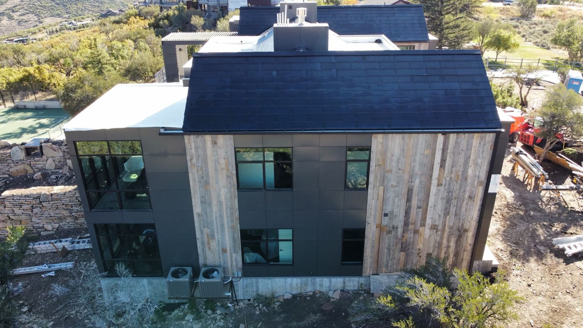 Modern home with black siding and natural wood panels; exterior view.