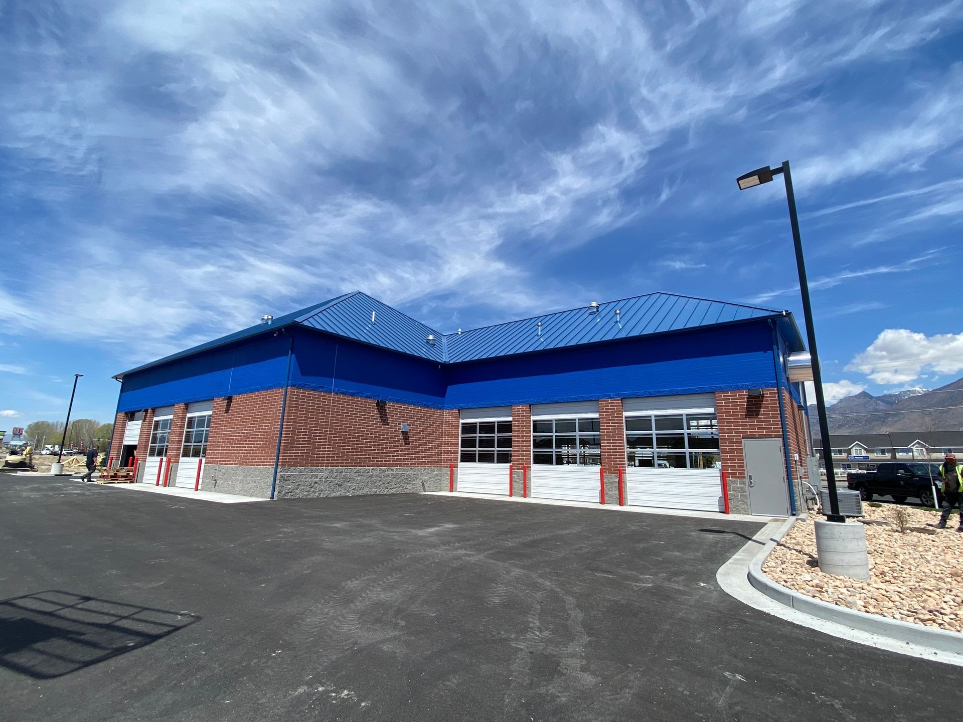 Car wash building with red brick and blue roof against a blue sky.